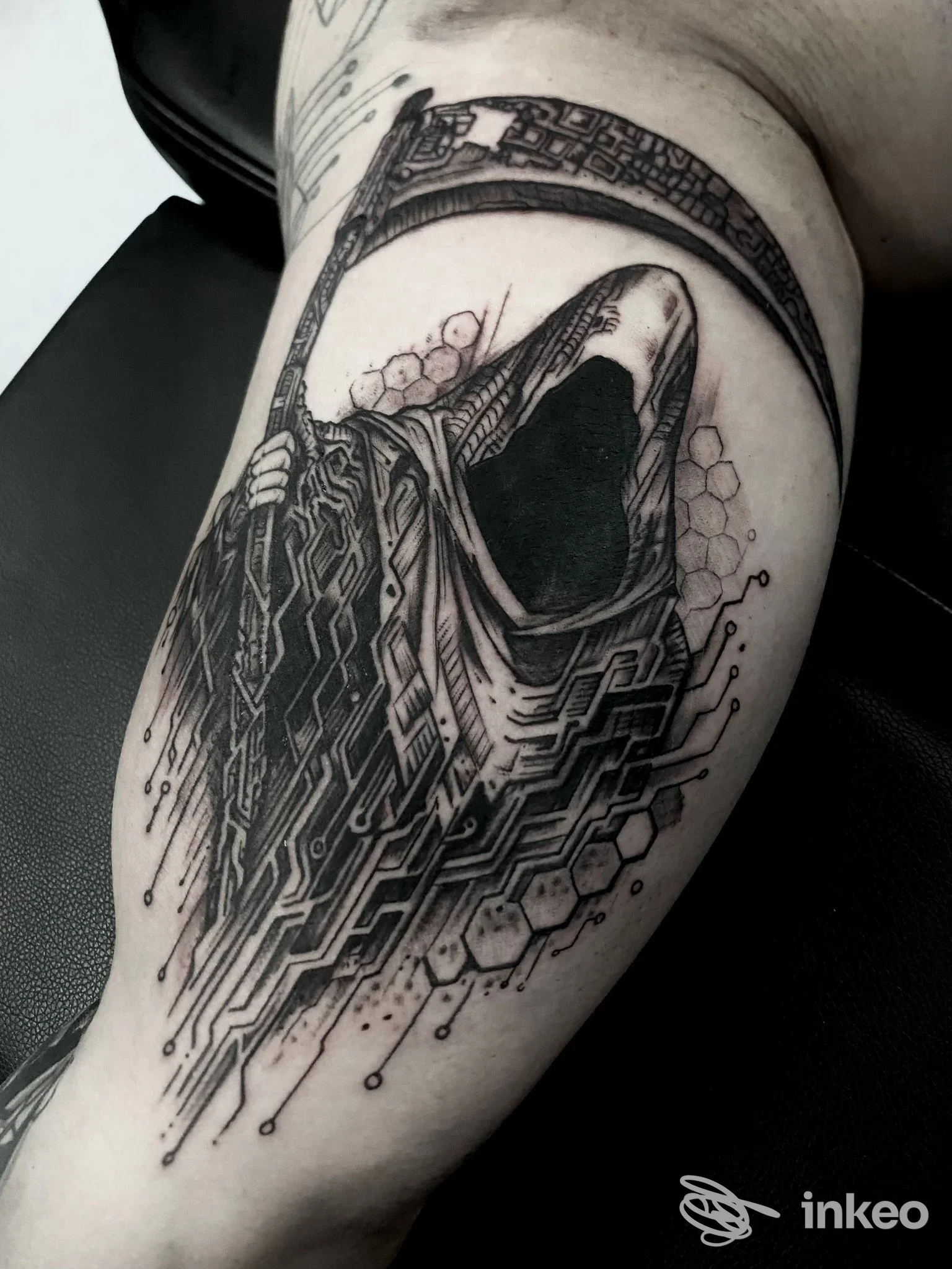 Tatuaggio scuro di figura incappucciata con falce e motivi geometrici sul braccio superiore, foto Rafa Ferrari Tattoo Studio, Imperia.