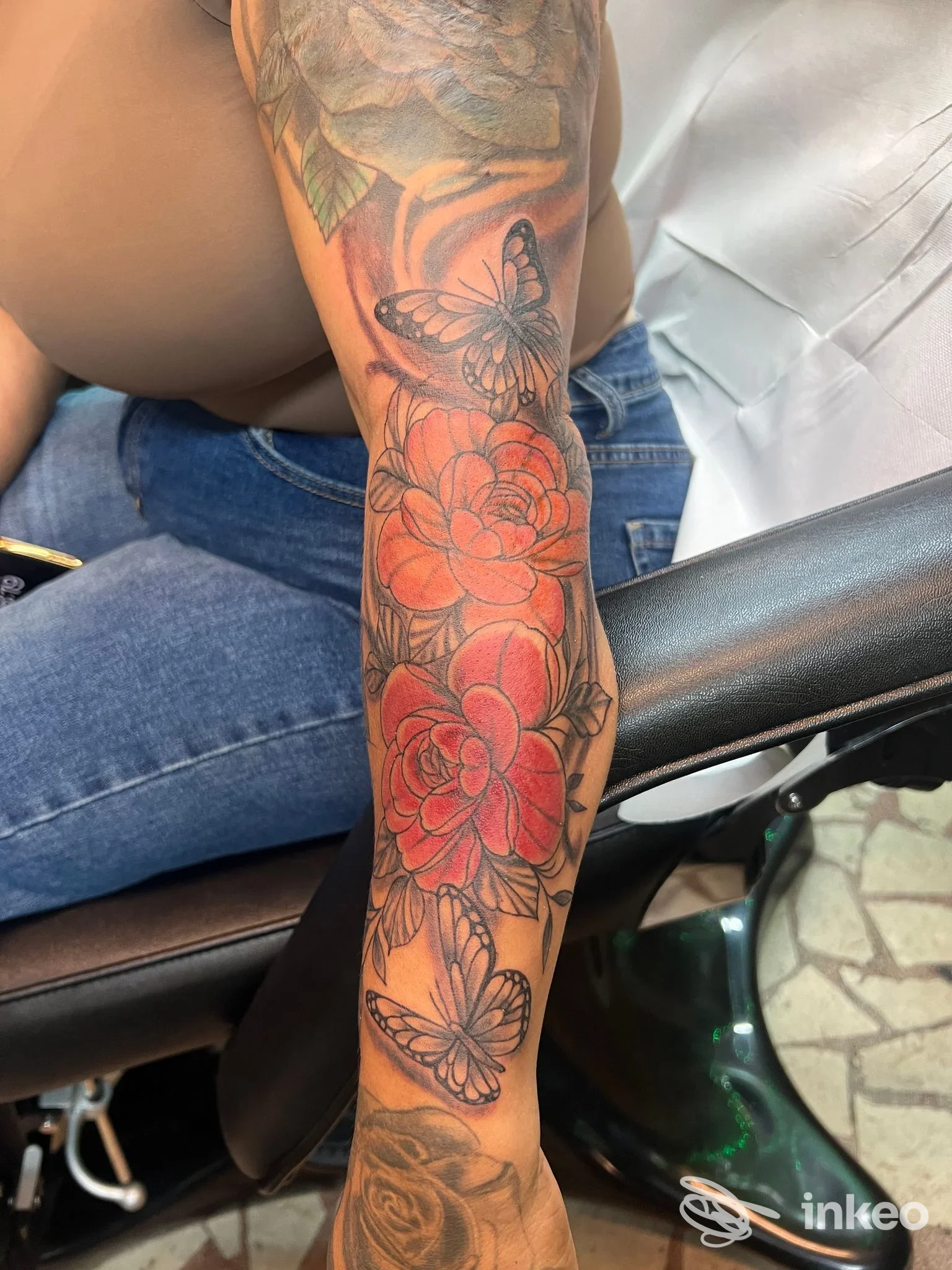 Avambraccio tatuato con fiori rossi e farfalle, foto per Rossini tattoo La Spezia.