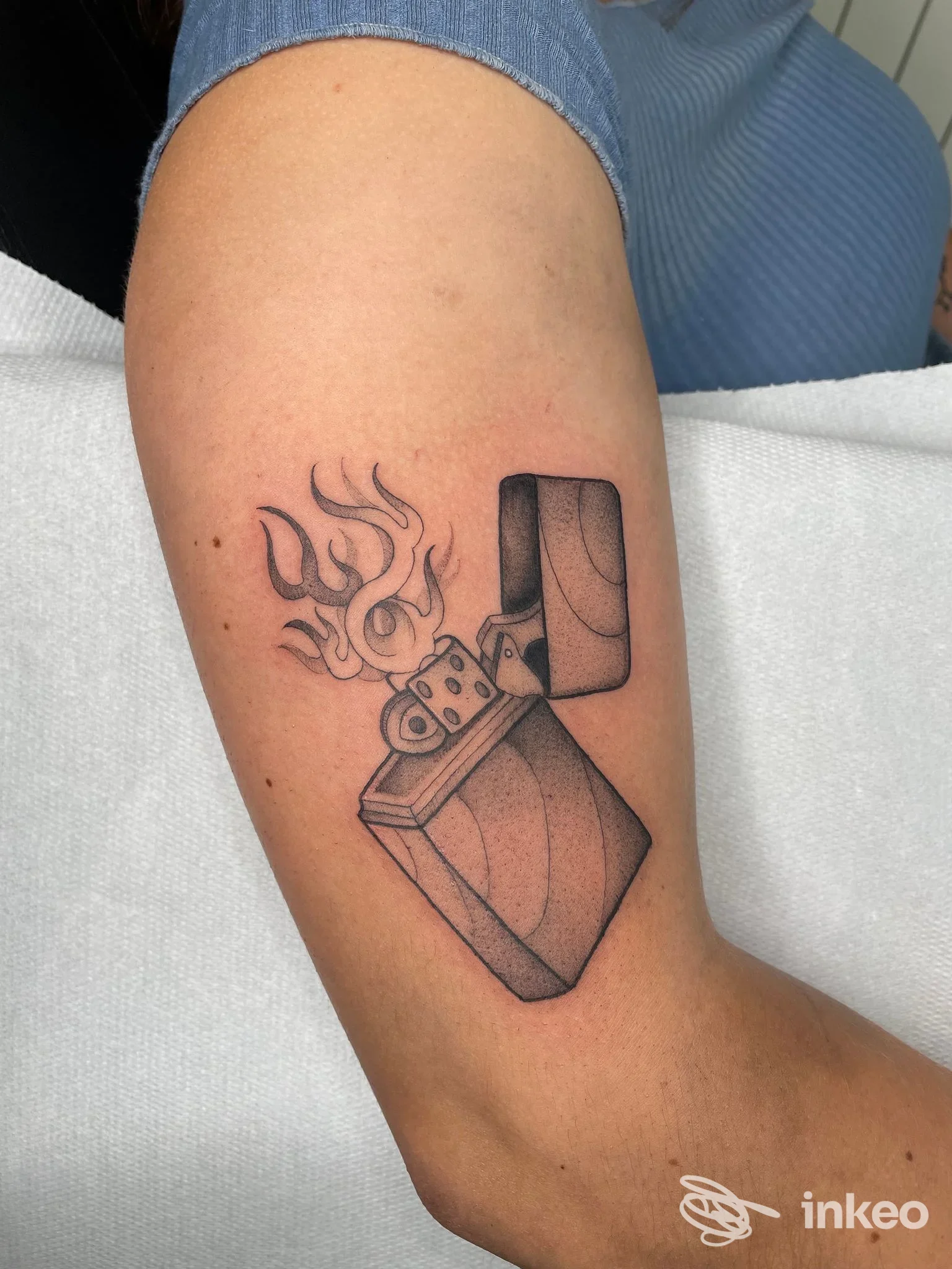 Tatuaggio di un accendino Zippo stilizzato con fiamma sull'avambraccio, lavoro di Simone Garbarino Tattoo a Gattorna.