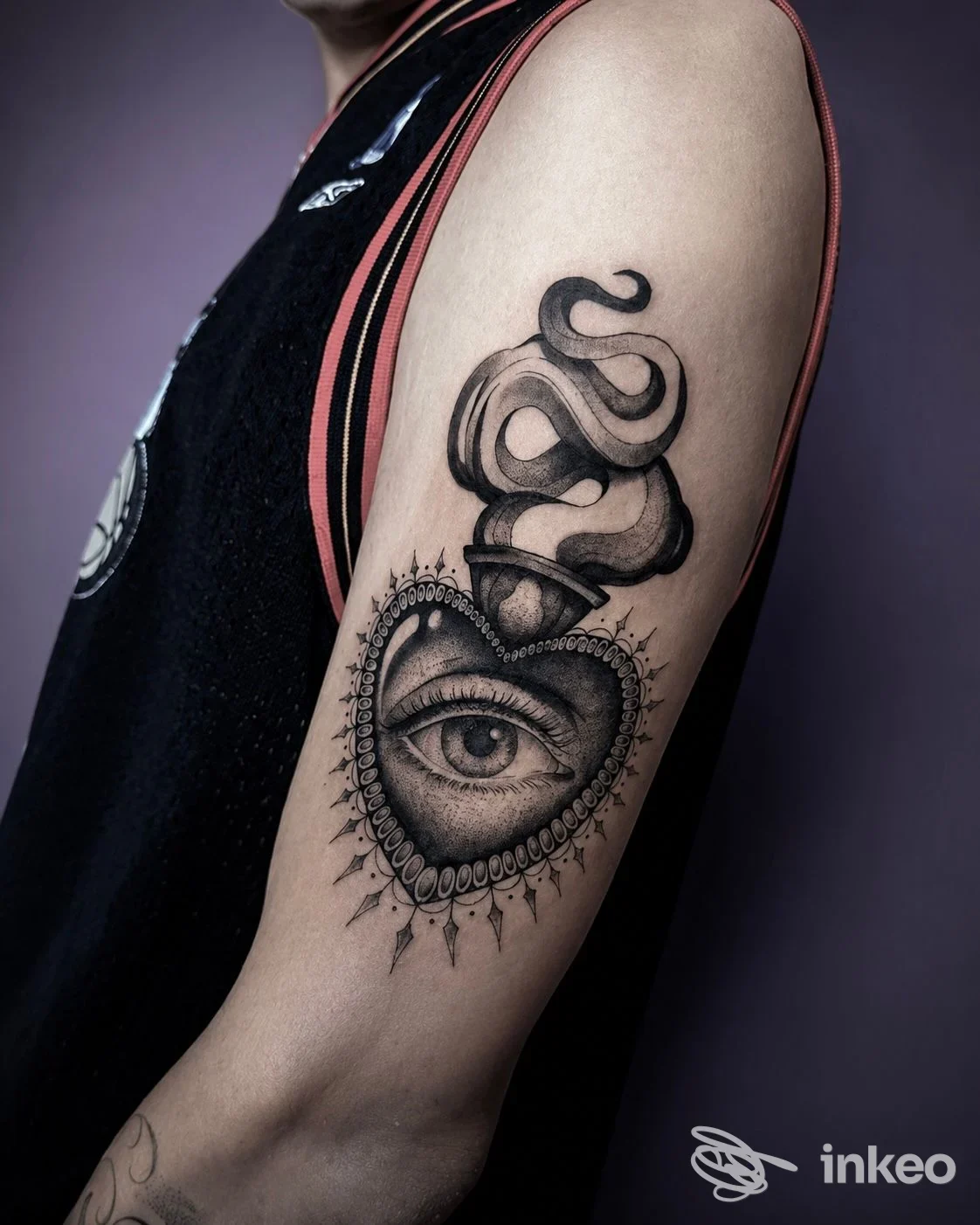 Tatuaggio su braccio superiore: cuore ornato con occhio centrale e elementi a nastro, foto per Sow ink Tattoo Studio, Genova.