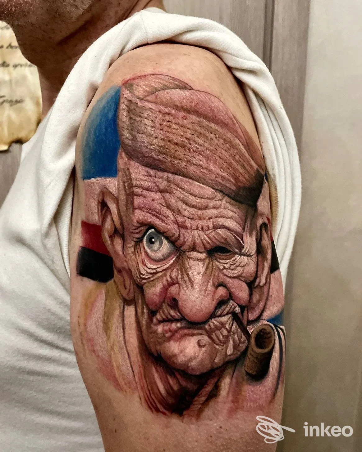 Ampio tatuaggio realistico di un volto anziano con pipa sul deltoide, fotografato presso Simo Art Tattoo a Genova.
