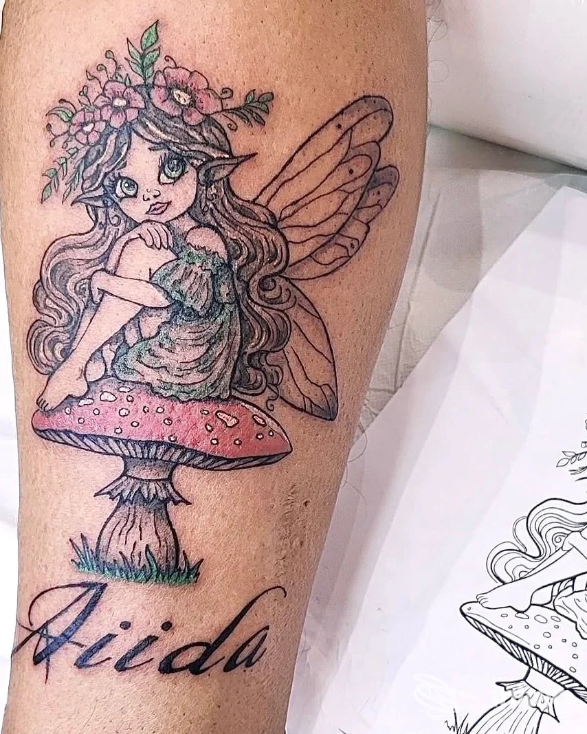 Tatuaggio di una fata seduta su un fungo con nome in corsivo, eseguito da Stewie Art Tattoo a Genova, sul polpaccio.