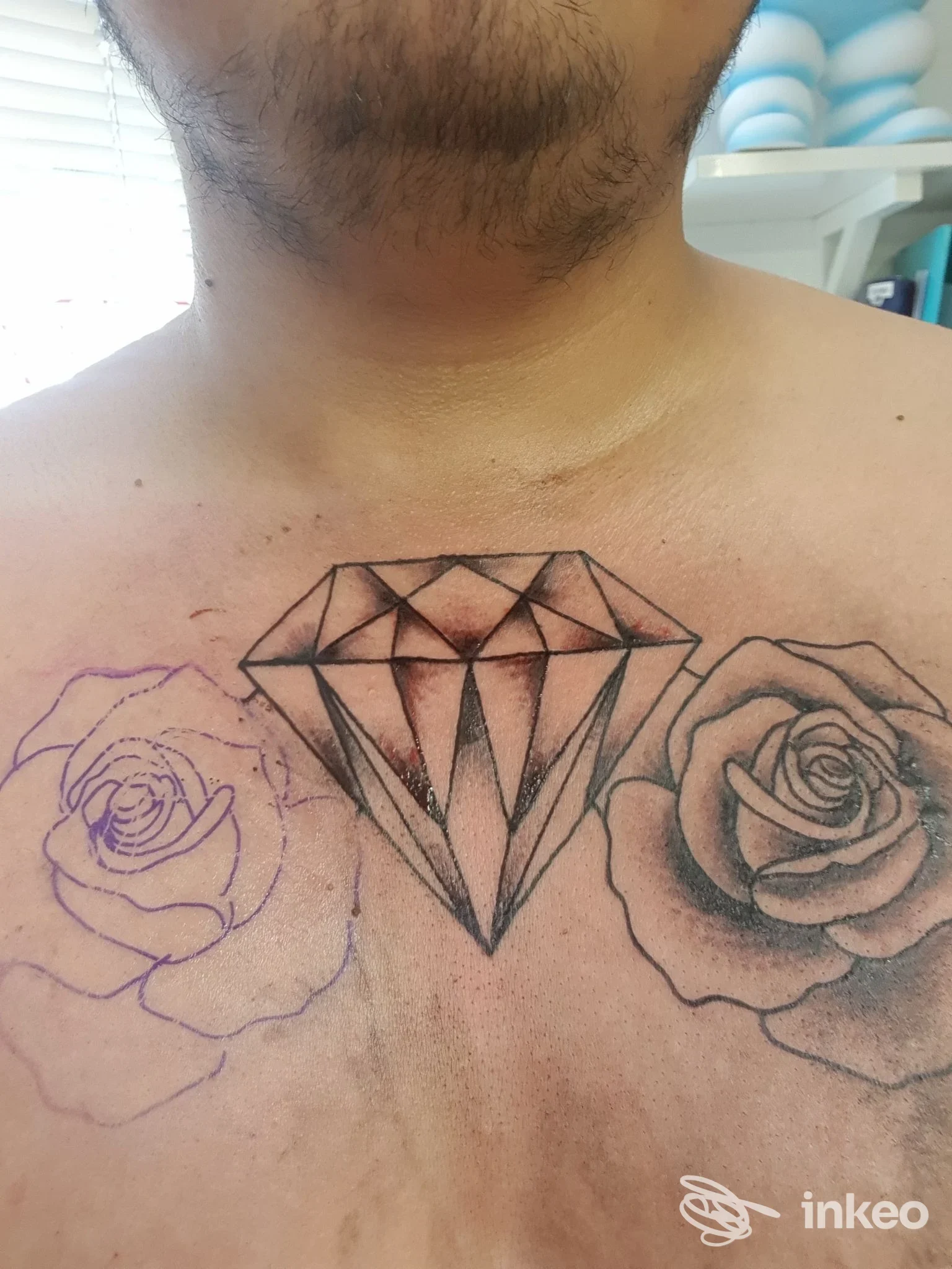 Primo piano sul petto con un diamante tatuato al centro e bozze di rose ai lati, Tattoo & Piercing Club Sarzana, Sarzana.