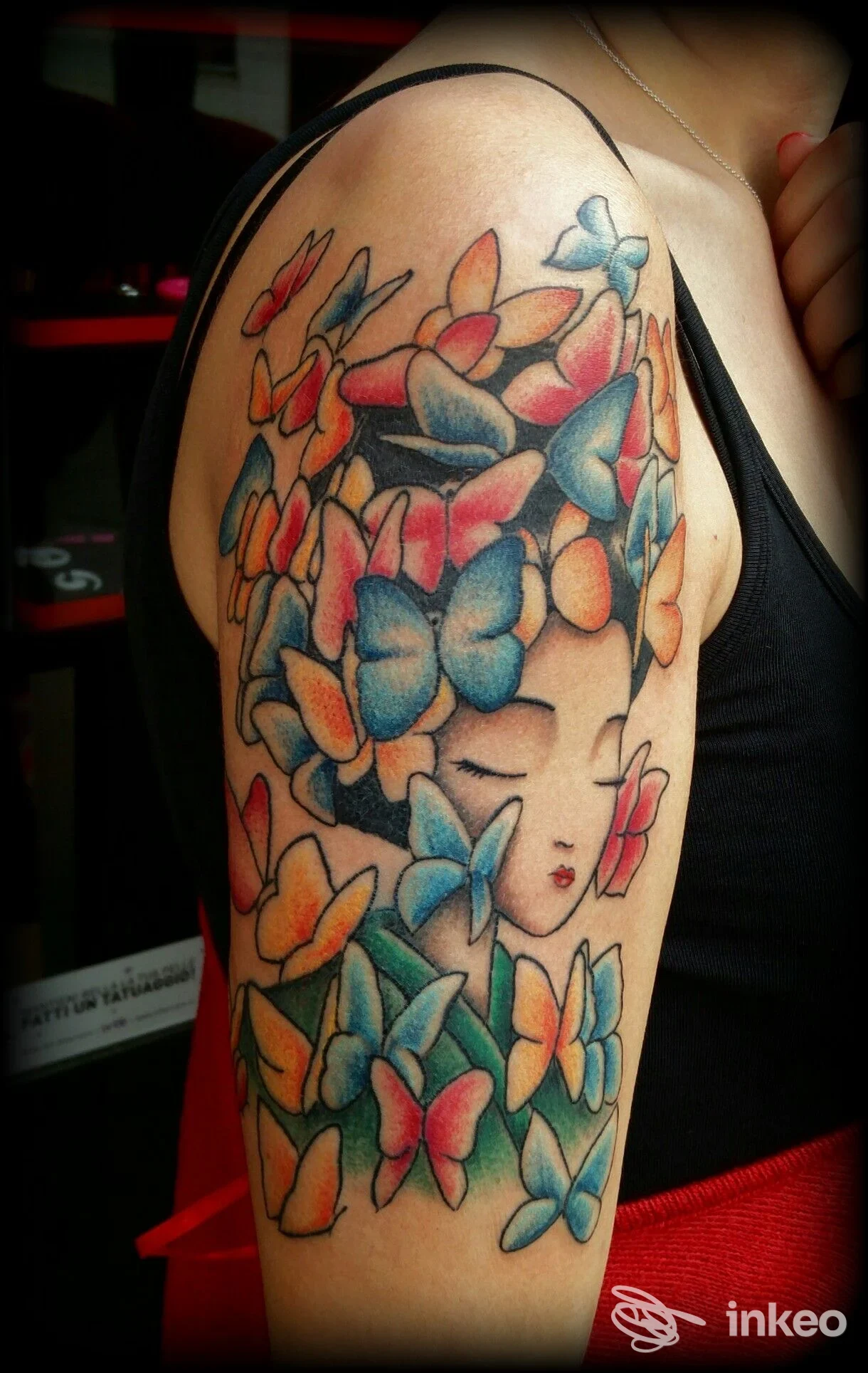 Tatuaggio colorato a farfalle e volto stilizzato sul braccio superiore, Tattoo & Piercing Club Sarzana, Sarzana.