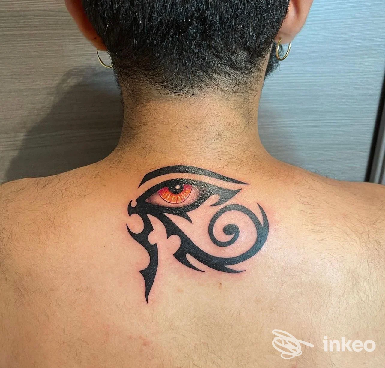 Tatuaggio a occhio stilizzato sulla parte alta della schiena, realizzato da Tattoo &Piercing White Moon a Imperia.