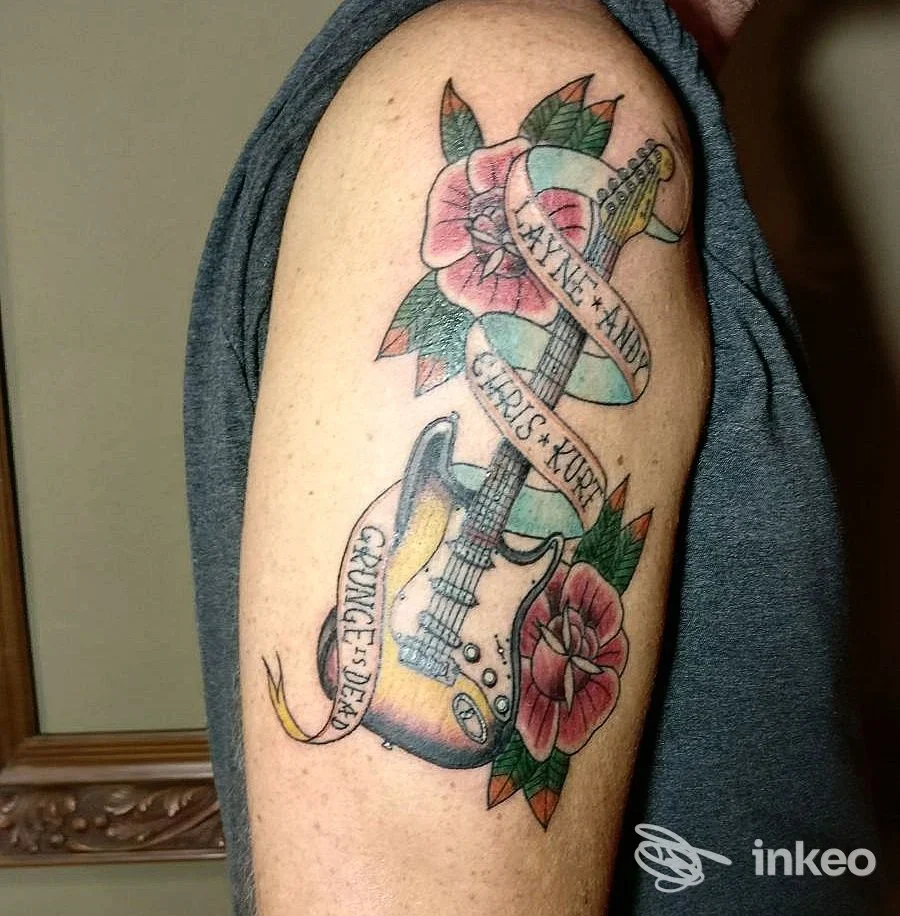 Tatuaggio su braccio con chitarra e fiori, foto per The Bishop Tattoo Studio, Laigueglia.