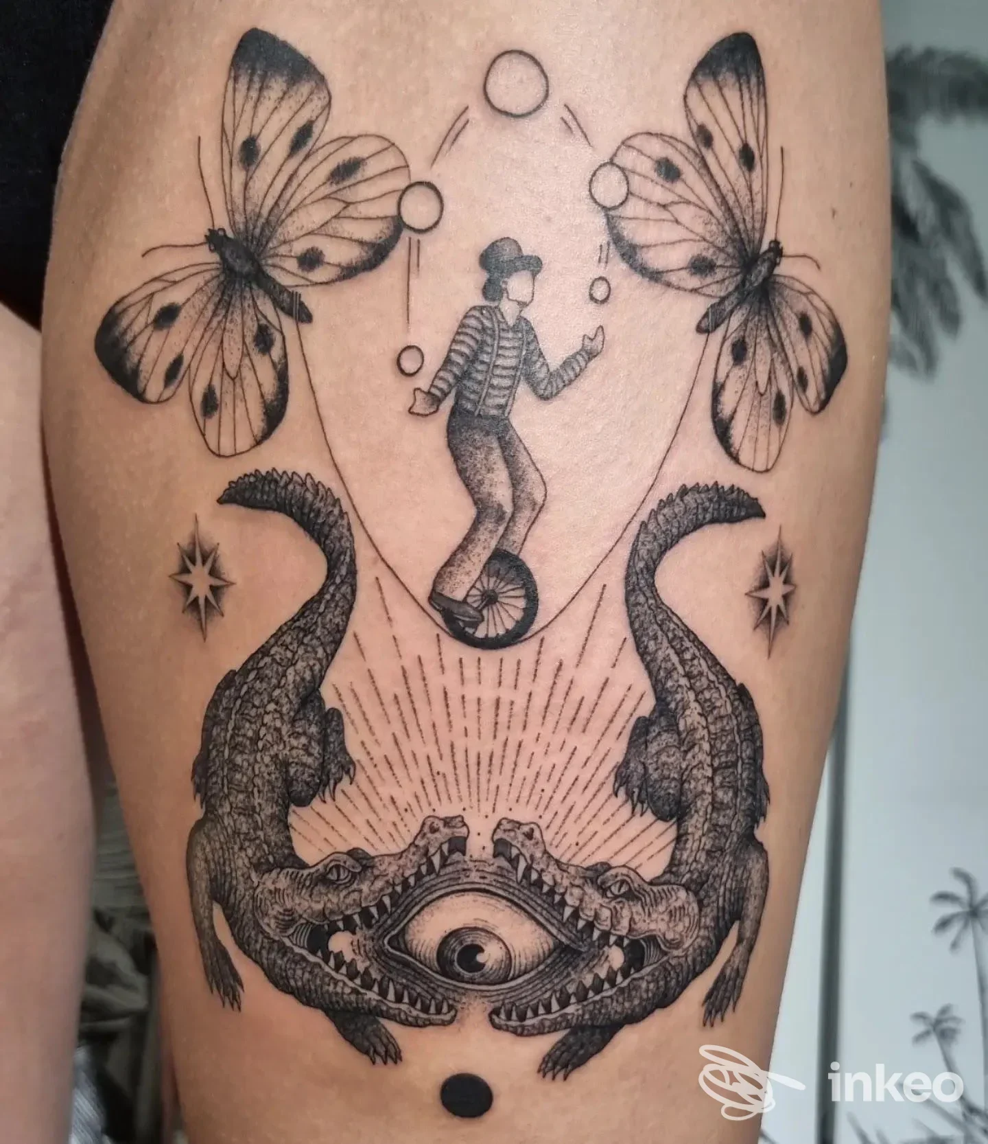 Tatuaggio in bianco e nero con coccodrilli, occhio centrale, farfalle e figura su monociclo, realizzato da The Pot tattoos & things a Genova.