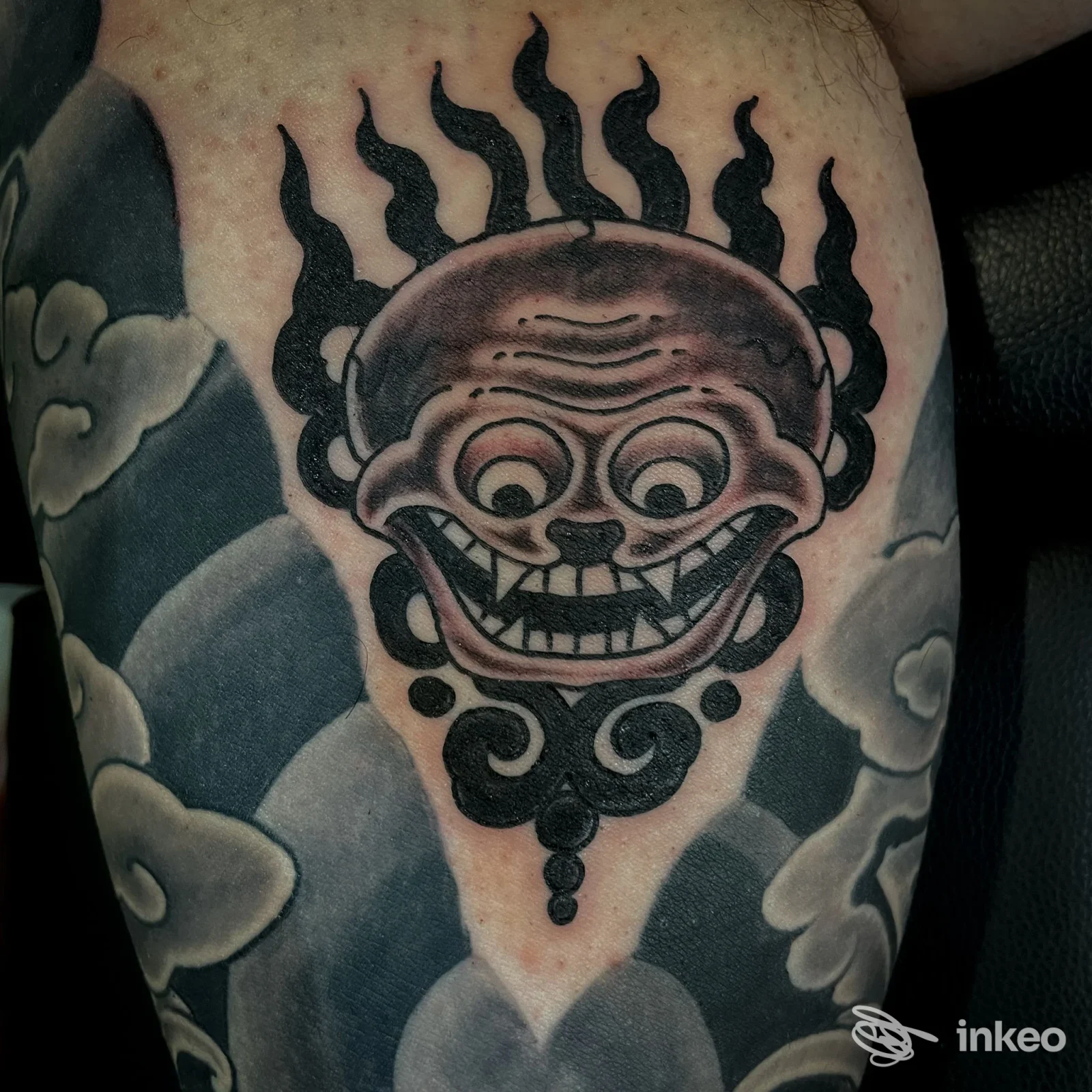 Tatuaggio nero su coscia con volto stilizzato e decorazioni, realizzato da The Pot tattoos & things a Genova.