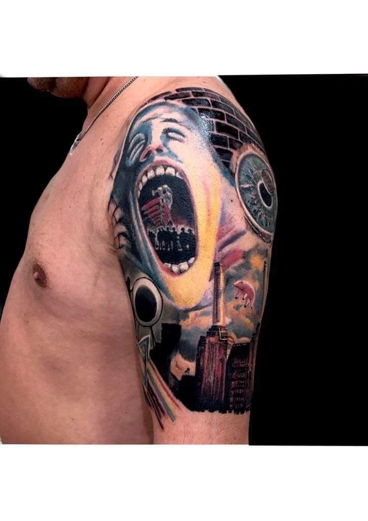 Tatuaggio colorato su spalla e braccio superiore, foto di lavoro realizzato da Tnt Tattoo a Genova che mostra un volto urlante e elementi urbani.