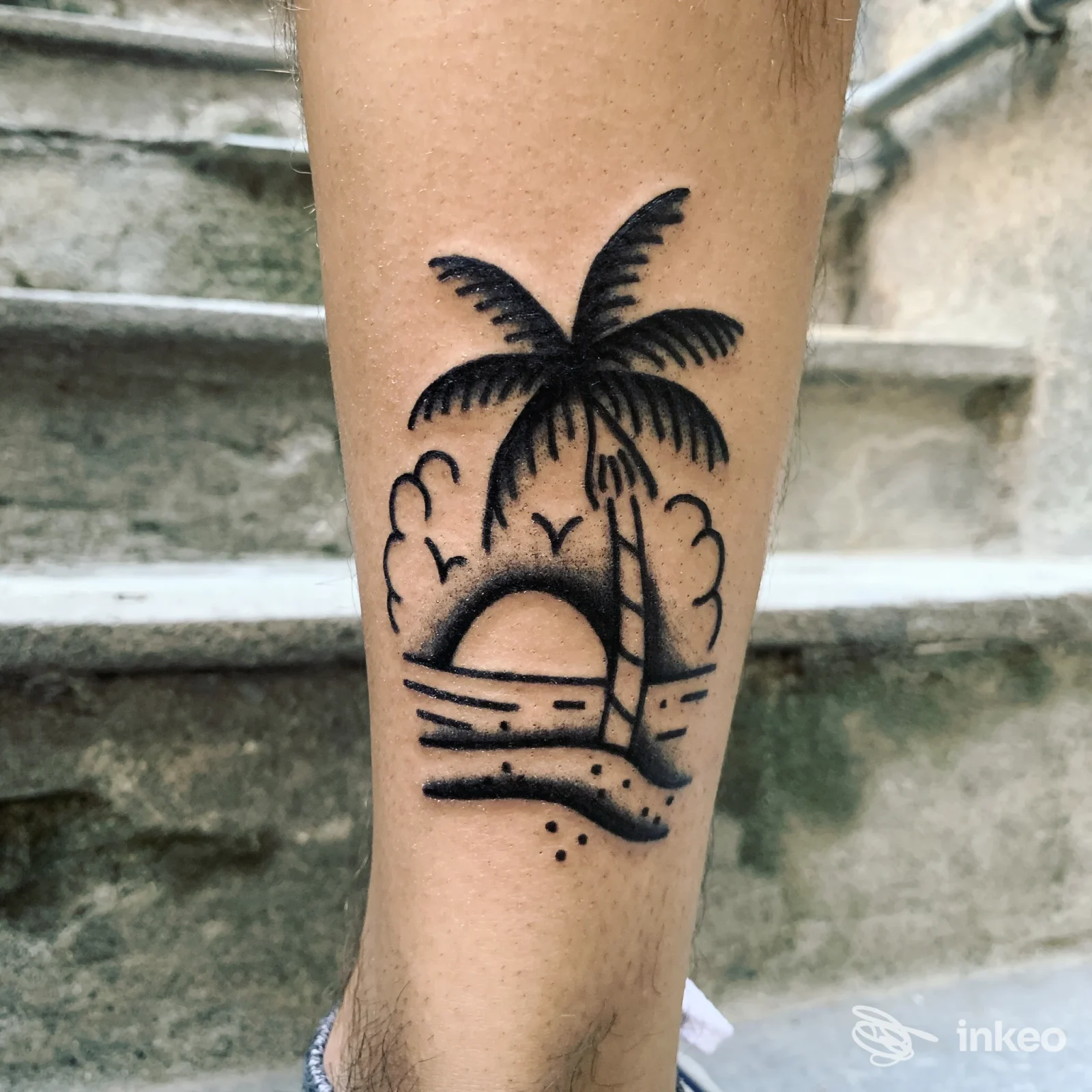Tatuaggio in nero di scena tropicale sul polpaccio, lavoro di Yuri Nani Tattooing a Varazze, primo piano della pelle.