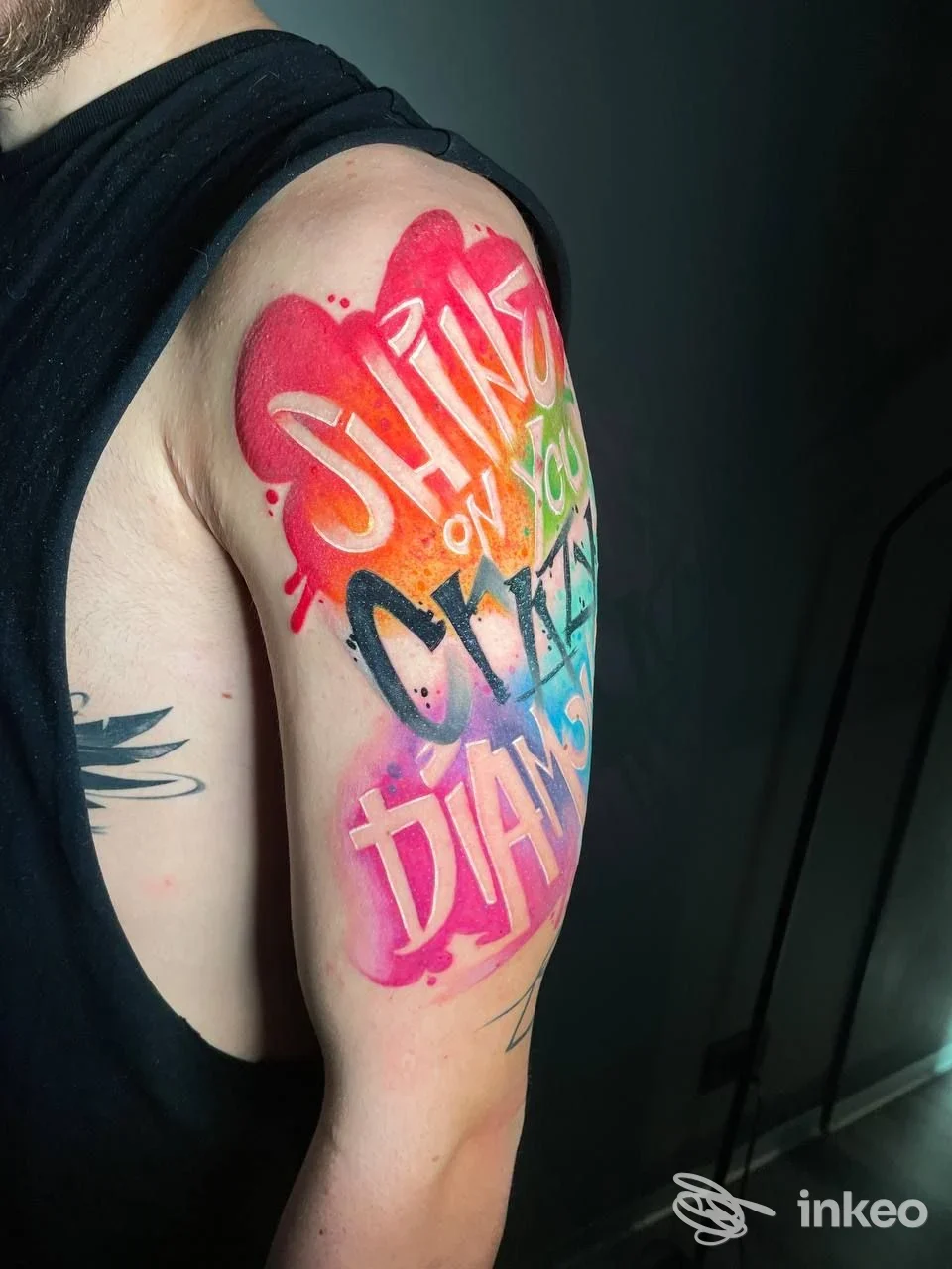 Tatuaggio colorato lettering su braccio superiore, foto fornita da Andrea Caso - Baby Skull Tattoo a Pavona.