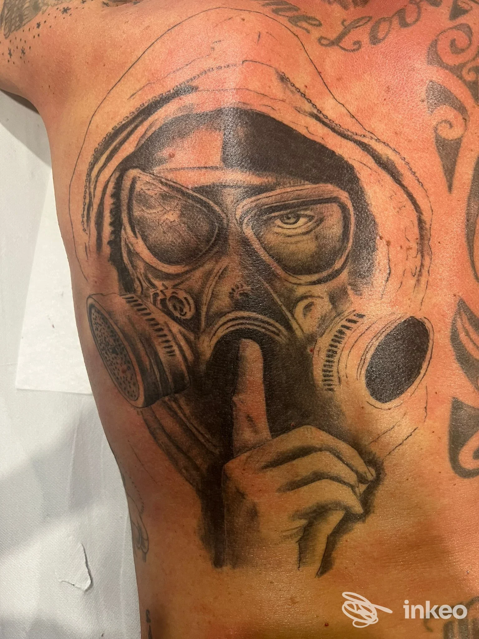 Tatuaggio black & grey su torace/fianco raffigurante una figura con maschera antigas, The Cult Tattoo Studio, Genova.