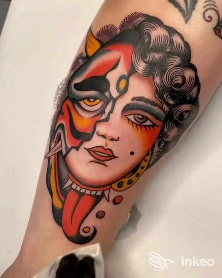 Tatuaggio neo-traditional su avambraccio mostrato da Banana Tattoo Studio, Vitorchiano: volto mascherato colorato con dettagli neri e rossi.