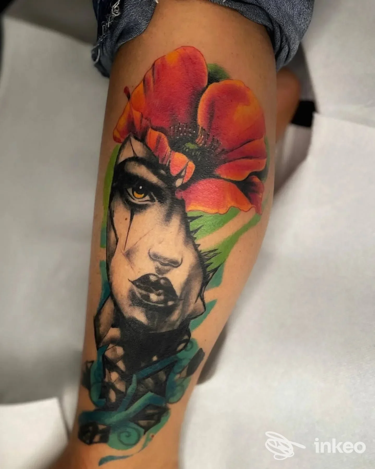 Tatuaggio colorato su polpaccio con volto stilizzato e grande fiore, Banana Tattoo Studio a Vitorchiano.