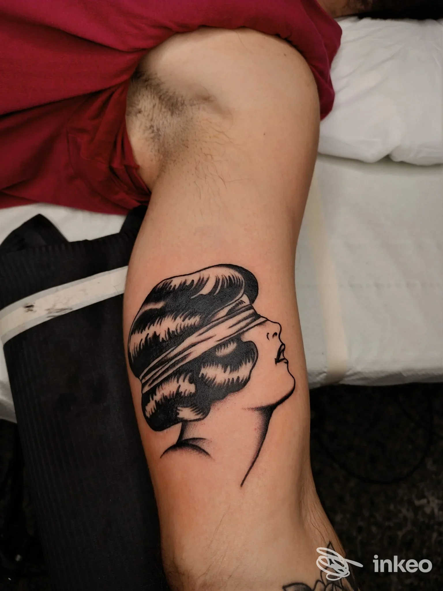 Avambraccio con tattoo: profilo di una donna in stile silhouette, capelli pettinati, disegnato in inchiostro nero sulla pelle.