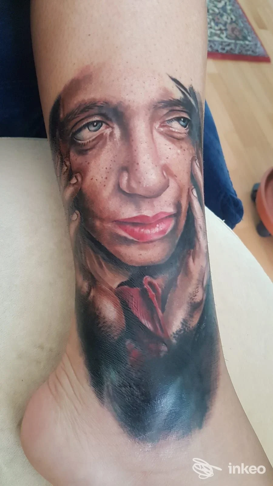 Tatuaggio realistico a colori raffigurante un ritratto con mani sulla caviglia, Tatuaggi & Piercing Nero Fluido Tattoo, Osteria Nuova.