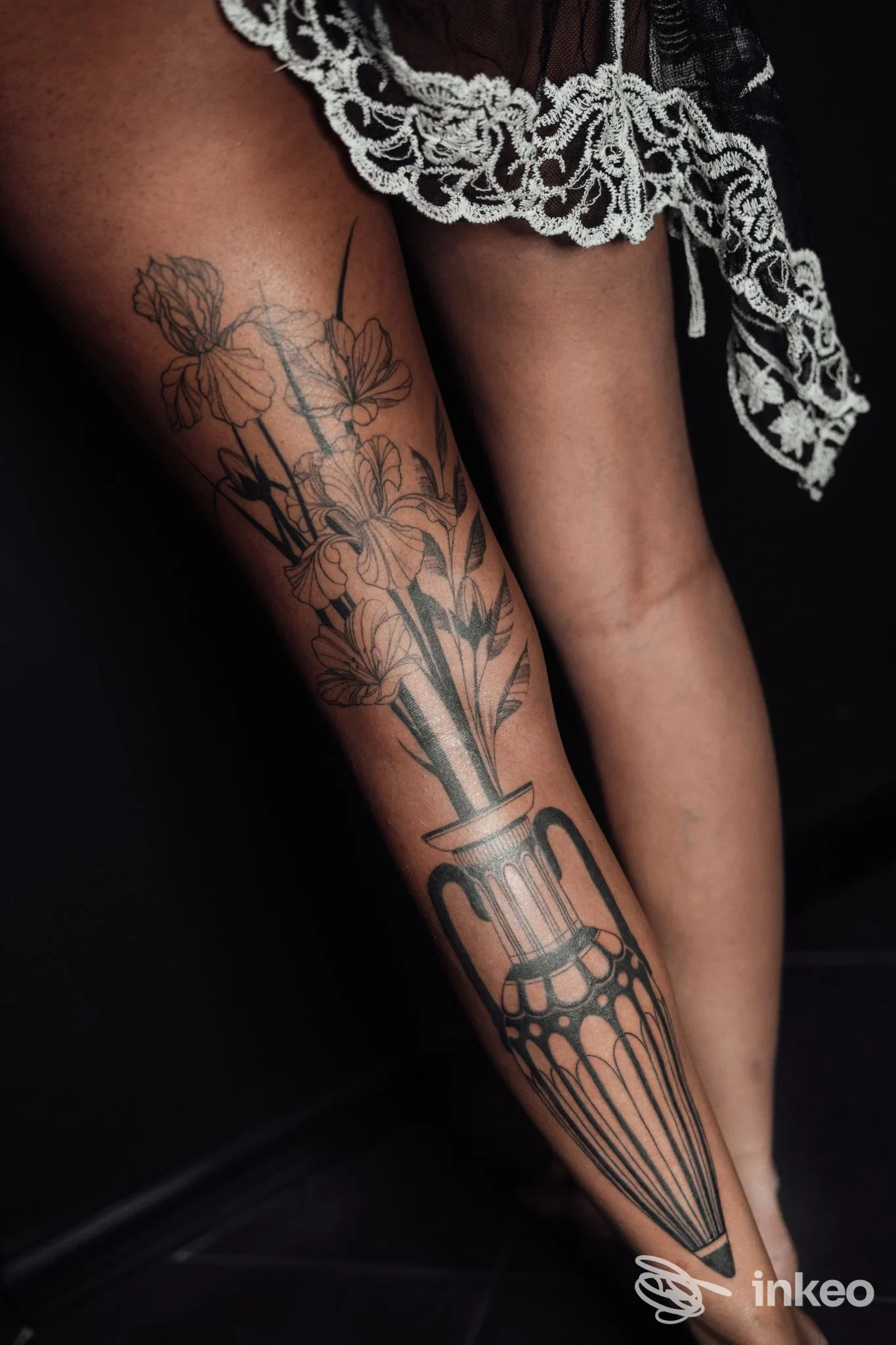 Dettaglio di un tatuaggio nero a tema floreale sul polpaccio e tibia, foto in luce drammatica. Eden Lab Tattoo Collective, Chieri.