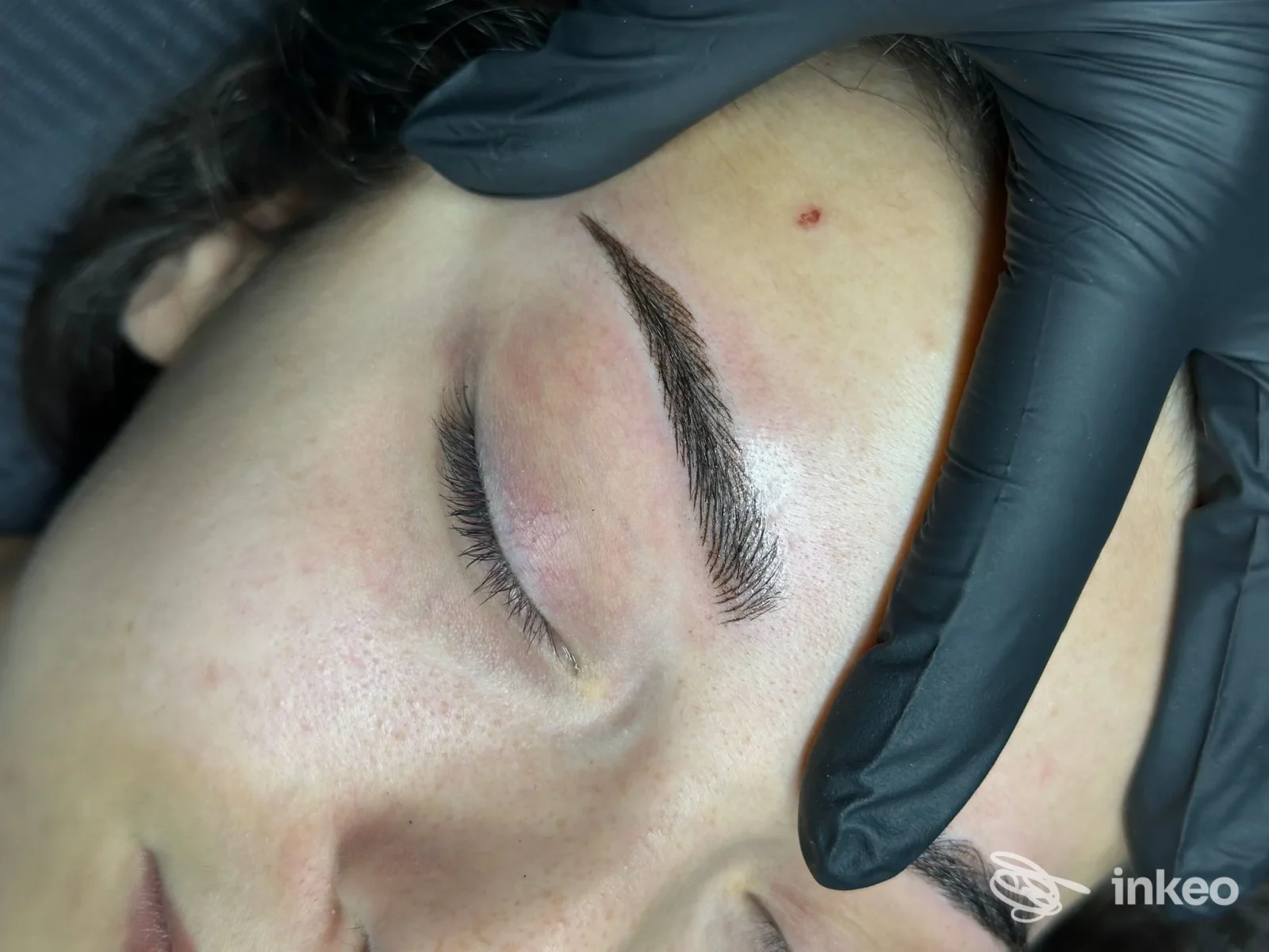 Primo piano di sopracciglia con trucco permanente eseguito, operatore con guanti neri. Maria Enrica Negrato - Oleggio.