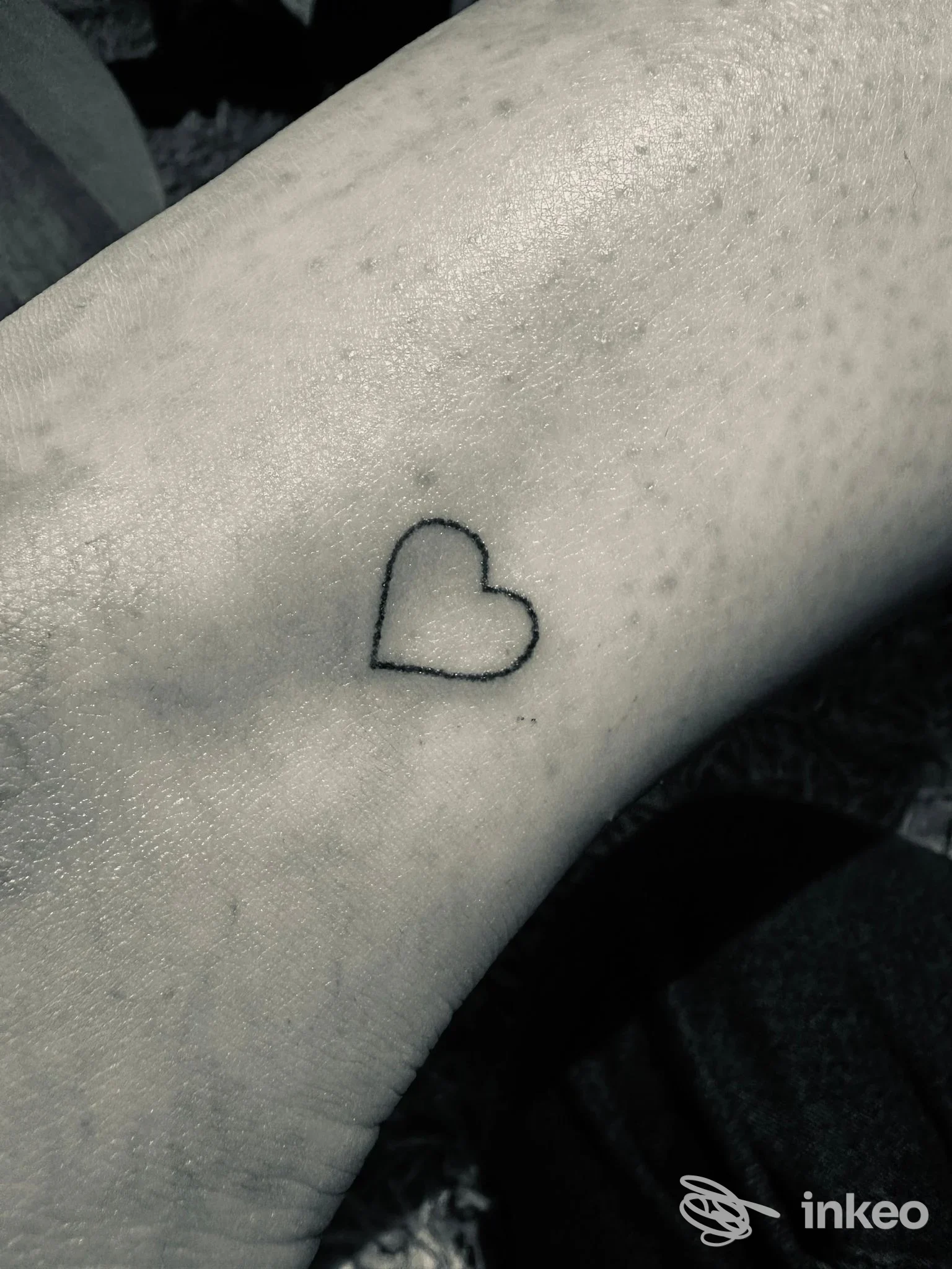 Piccolo tatuaggio a contorno a forma di cuore sul polso, linea nera sottile su pelle reale. Pier Arcudi - Torino