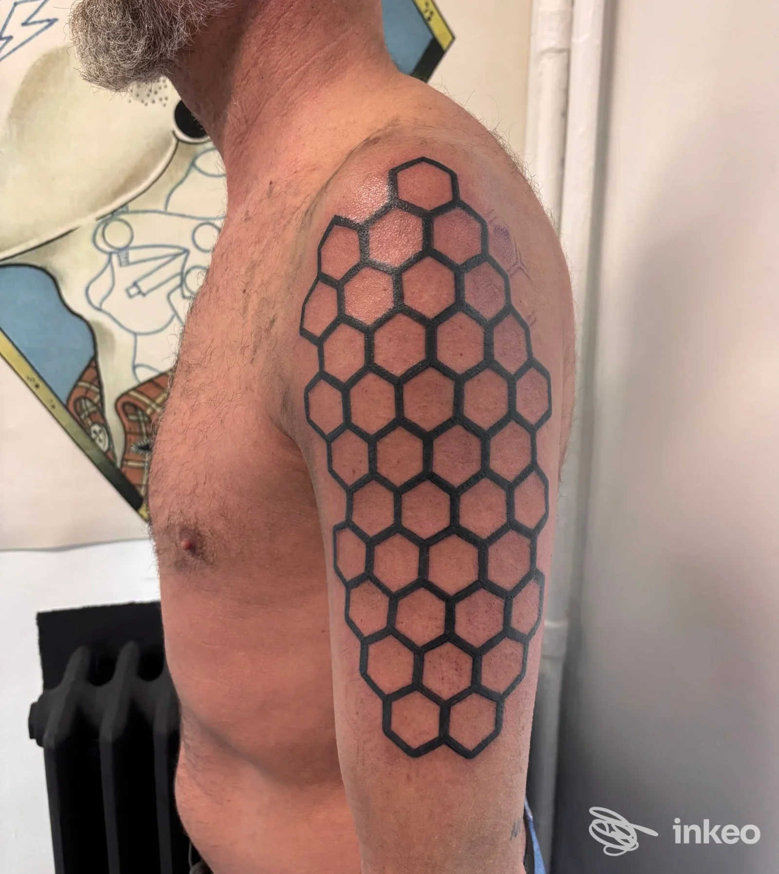 Tatuaggio geometrico a nido d'ape sull'omero di un uomo, Linea Nera Tattoo & Piercing, Torino.