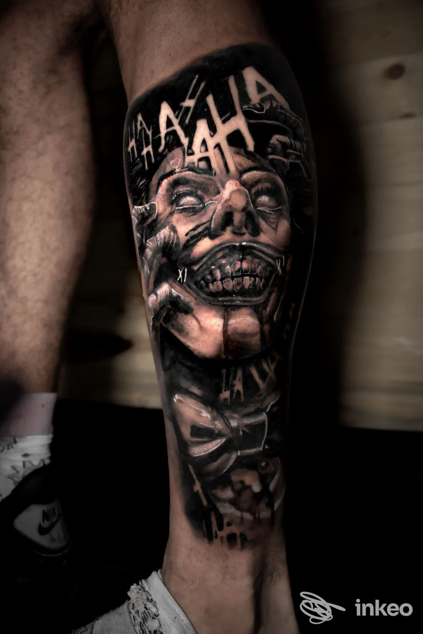 Tatuaggio realistico in bianco e nero su polpaccio con volto grottesco, Artemisia Luxury Body Piercing & Tattoo, Torino.