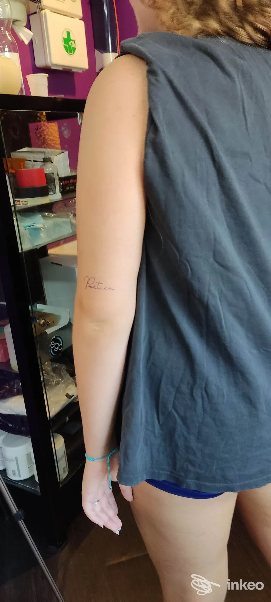 Braccio di una persona visto di lato, si intravede un piccolo tatuaggio in corsivo sulla pelle, senza volto visibile, ambiente interno dello studio Blood'n Soul Tattoo a Rozzano.