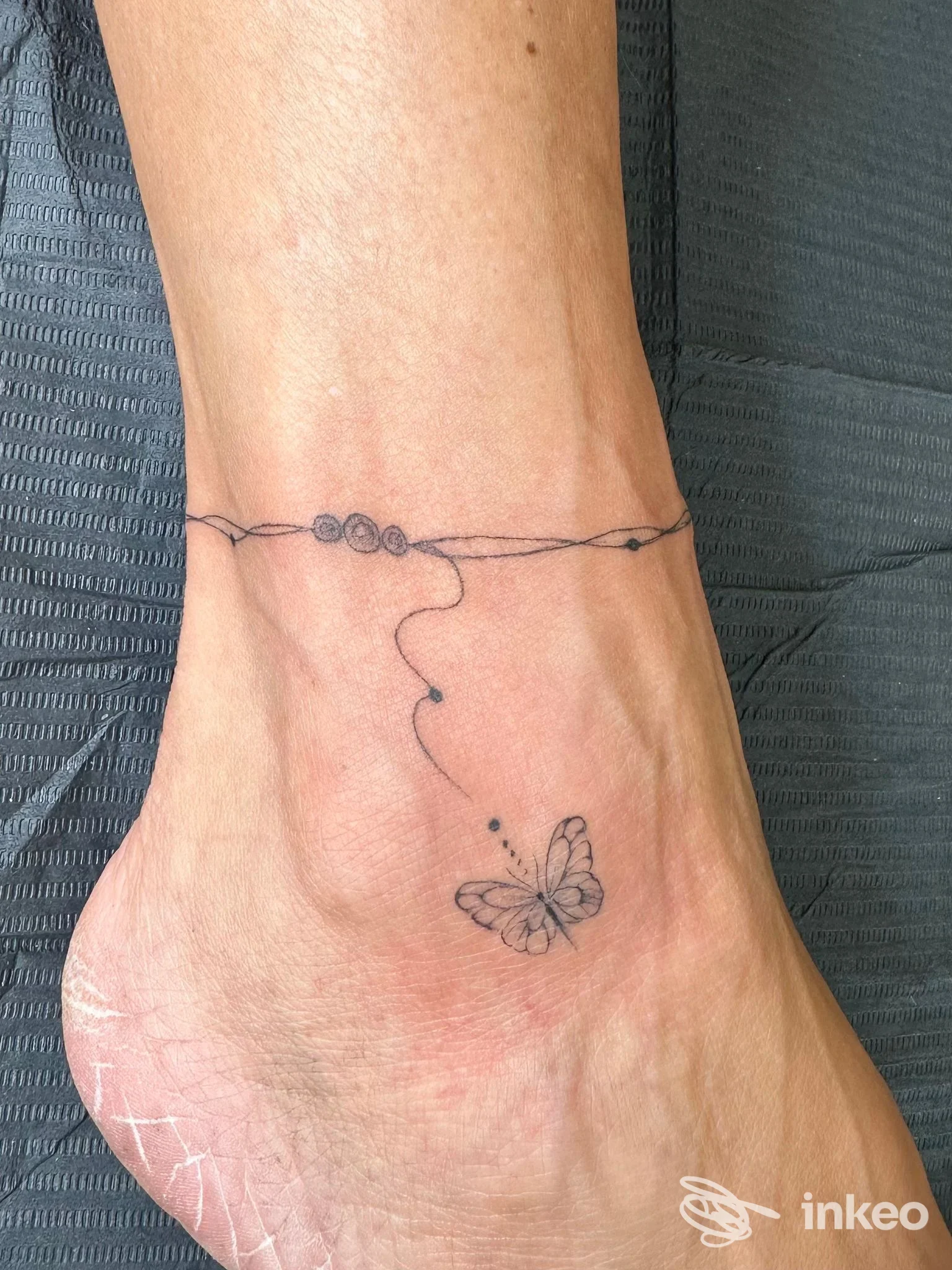 Tatuaggio minimal su caviglia con farfalla e filo, Taryn Chiereghin Tattoo & Pmu, Sant'Antonino di Susa.