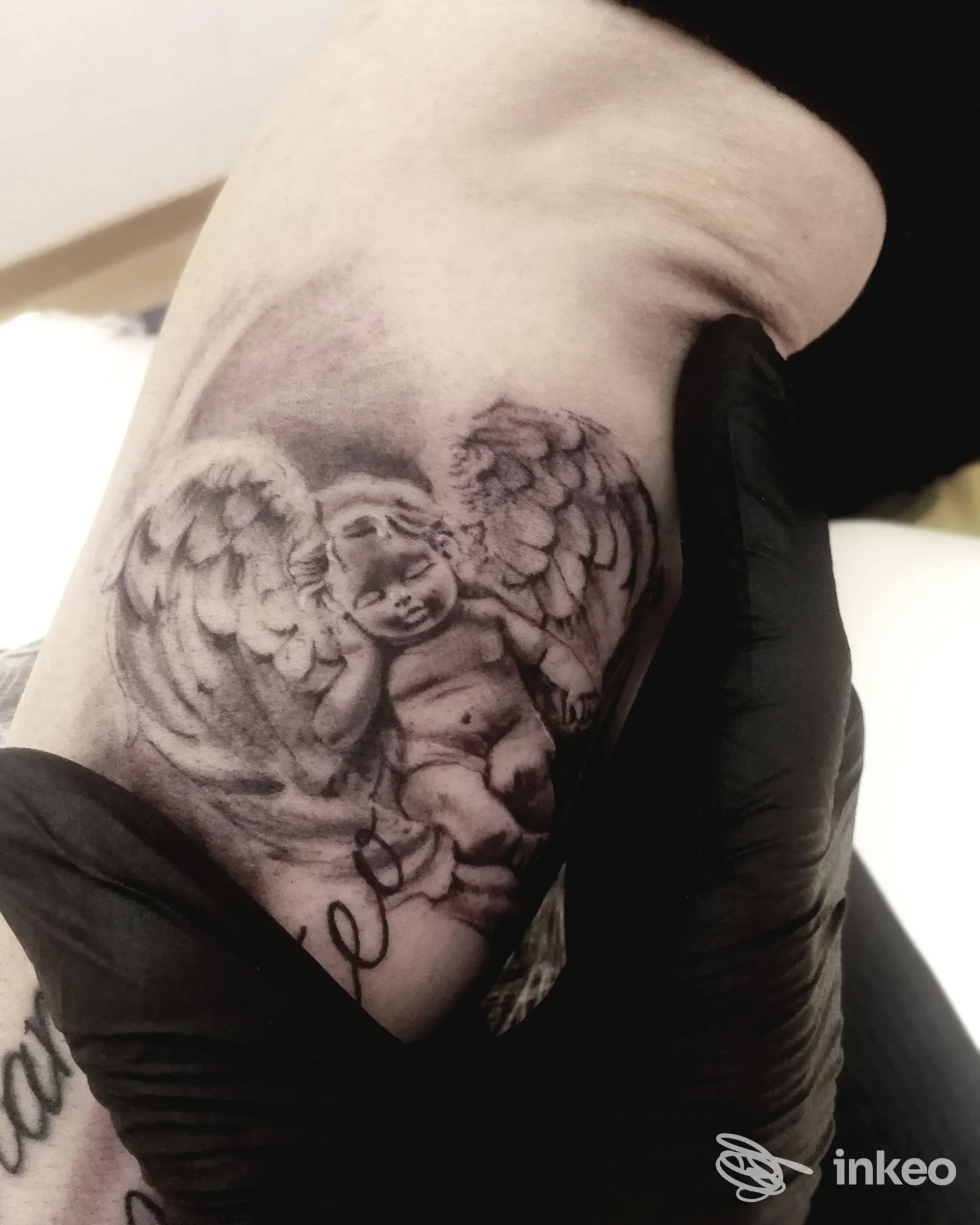 Tatuaggio black & grey di un putto sull'avambraccio, foto dello studio Andrea Colaci Bamm Tattoo Artist a Castrignano del Capo.