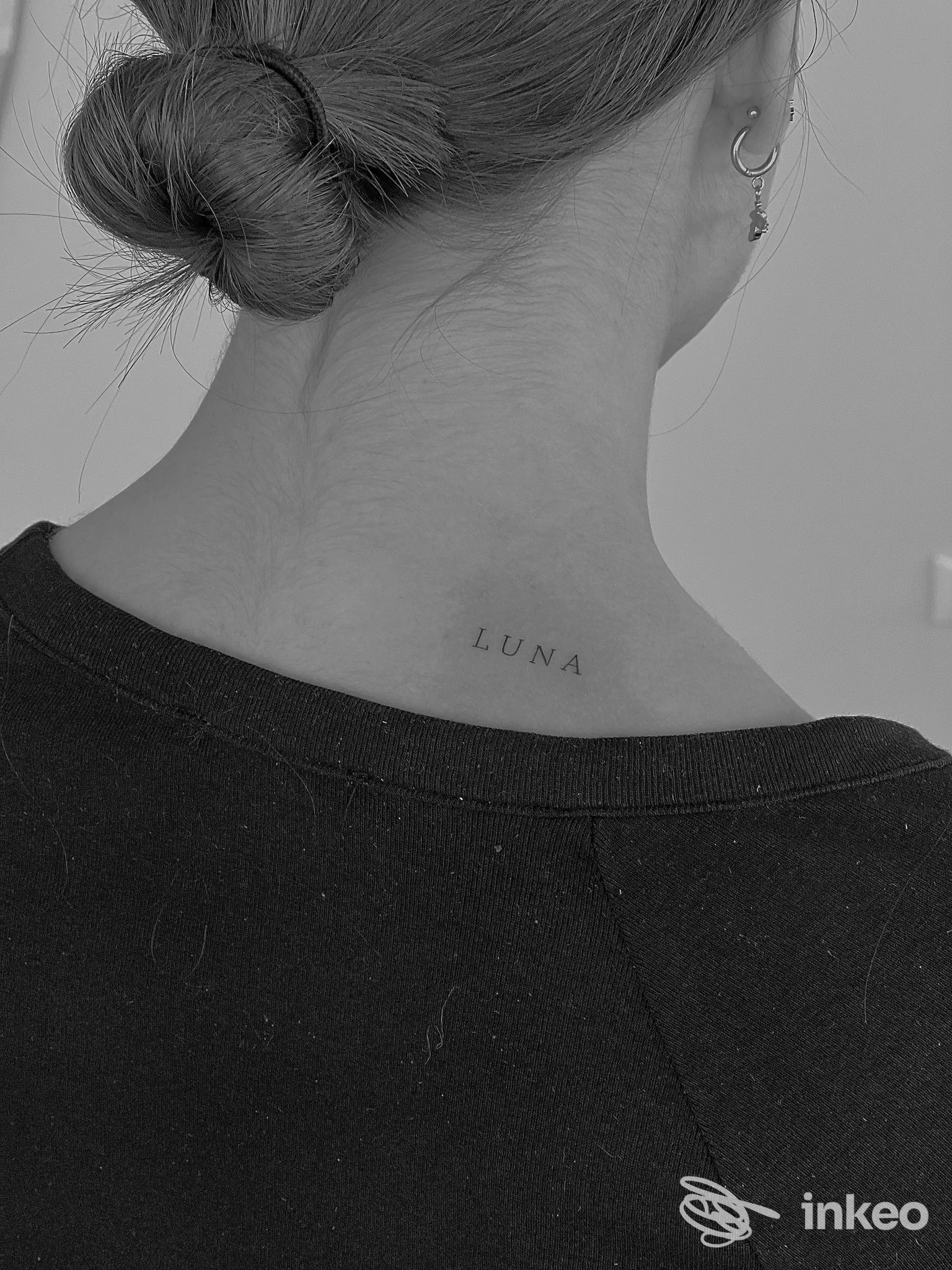 Nuca di una persona con una piccola tatto: la parola LUNA sulla pelle.