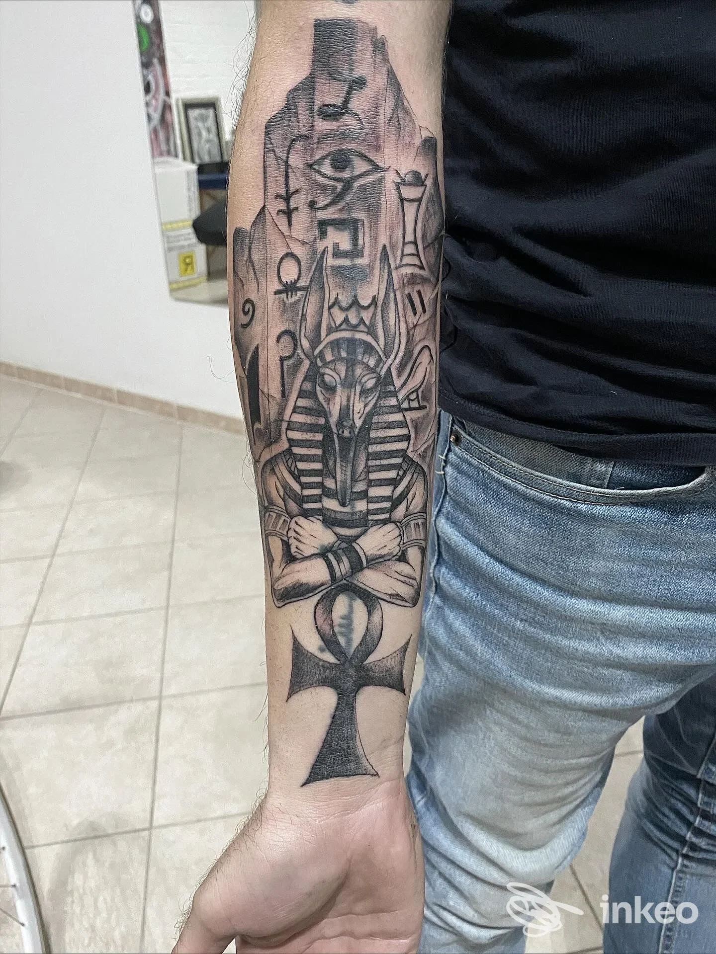 Tatuaggio nero e grigio a tema egizio sull'avambraccio, realizzato da ThemysticarTattoo a Muravera, vista frontale dell'avambraccio.