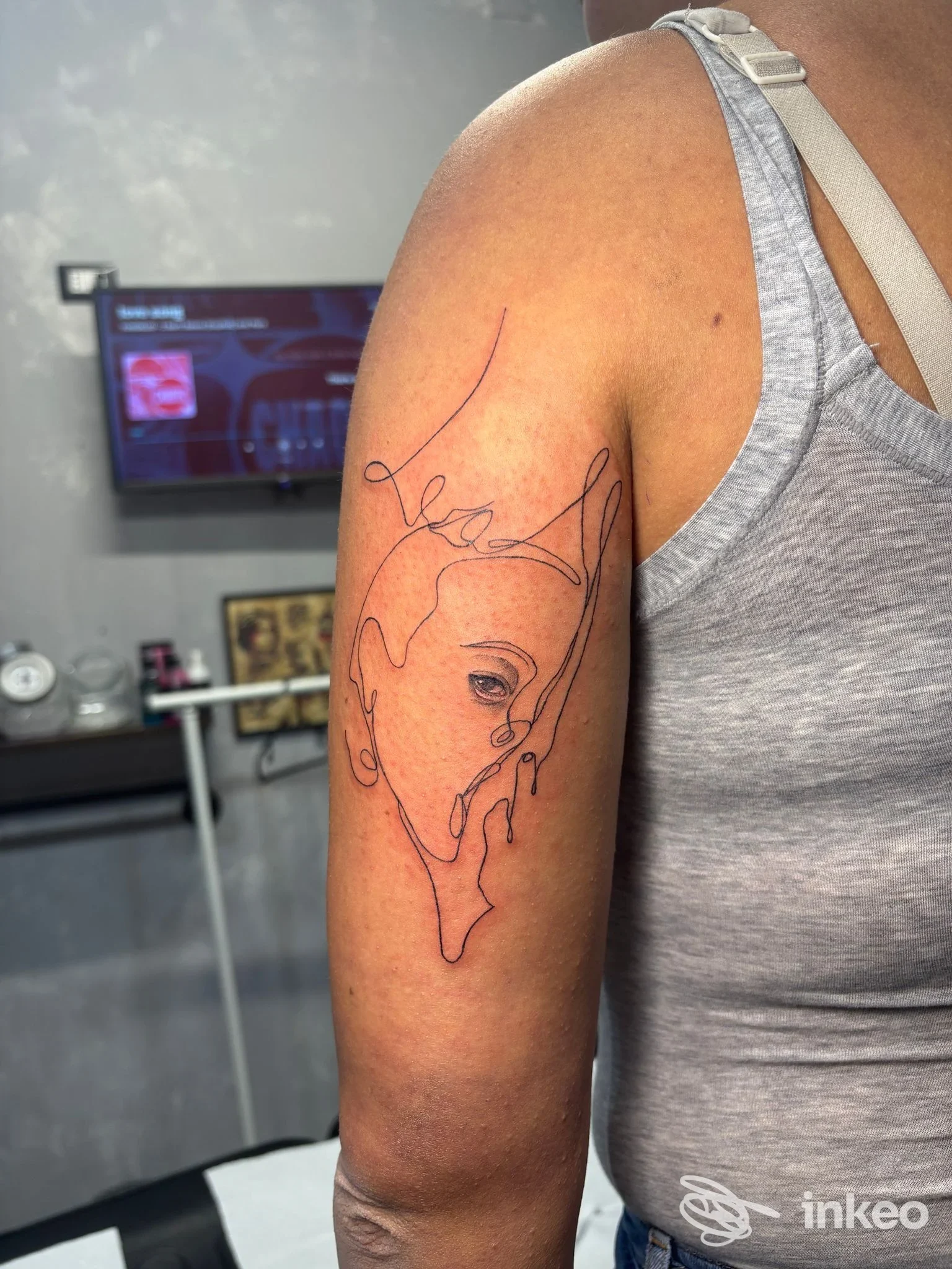 Tatuaggio lineare di un volto sul braccio superiore, foto scattata presso Space Tattoo Studio a Cecina.