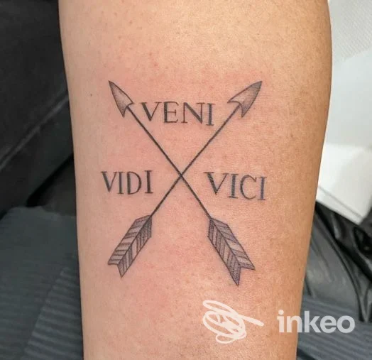 Tatuaggio sull'avambraccio con due frecce incrociate e la scritta 'VENI VIDI VICI', realizzato da Kutur tattoo Di Prucher Erika a San Giovanni Valdarno.