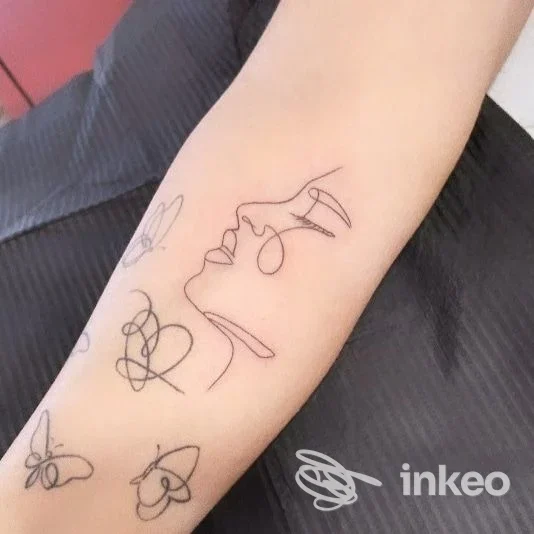 Tatuaggi linework neri su avambraccio: profilo stilizzato, cuori e farfalle. Immagine fornita da Kutur tattoo Di Prucher Erika, San Giovanni Valdarno.