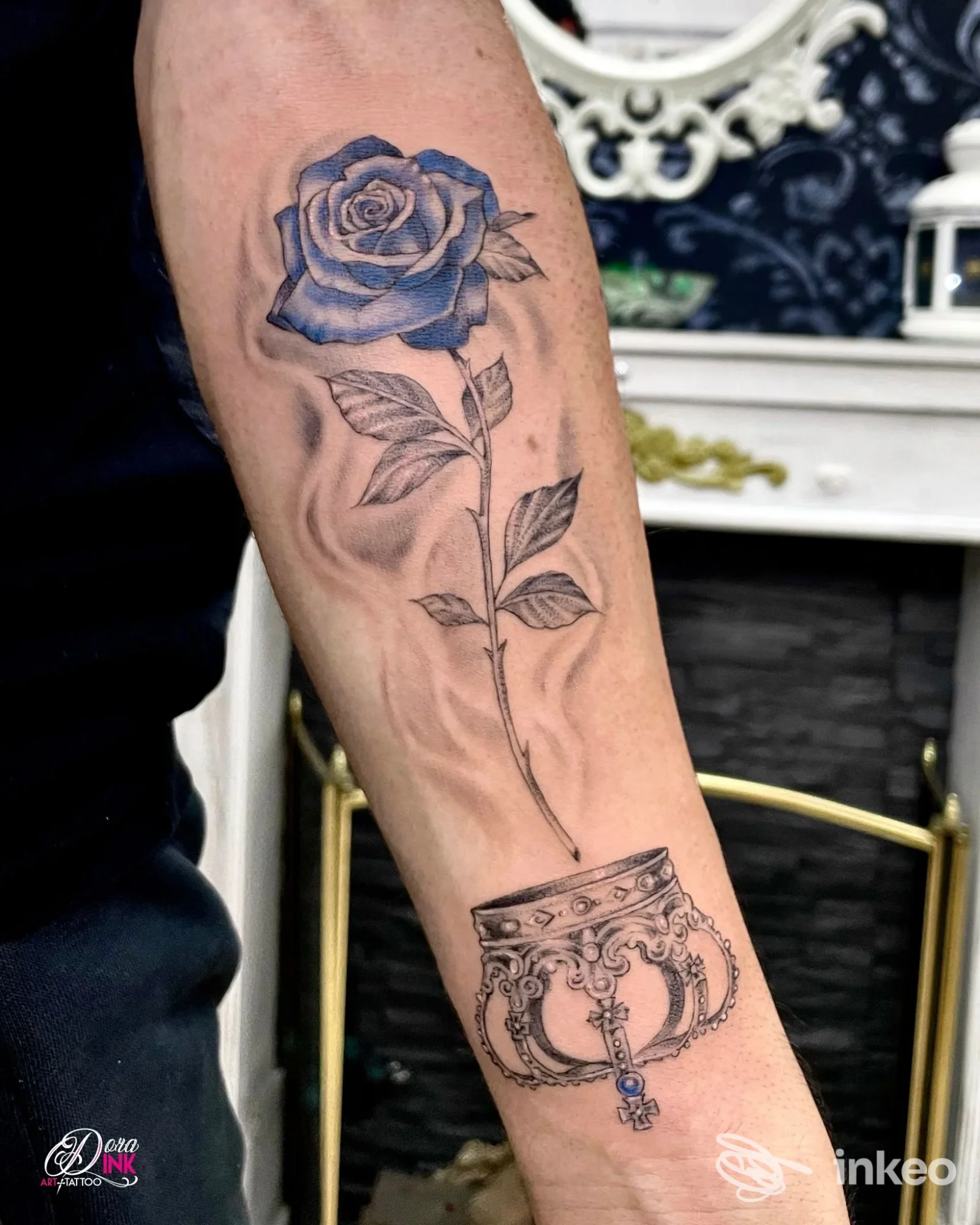 Tatuaggio di una rosa blu con gambo e un ornamento/bracciale decorativo sull'avambraccio, scatto dello studio Dora Ink Art & Tattoo a Saonara.
