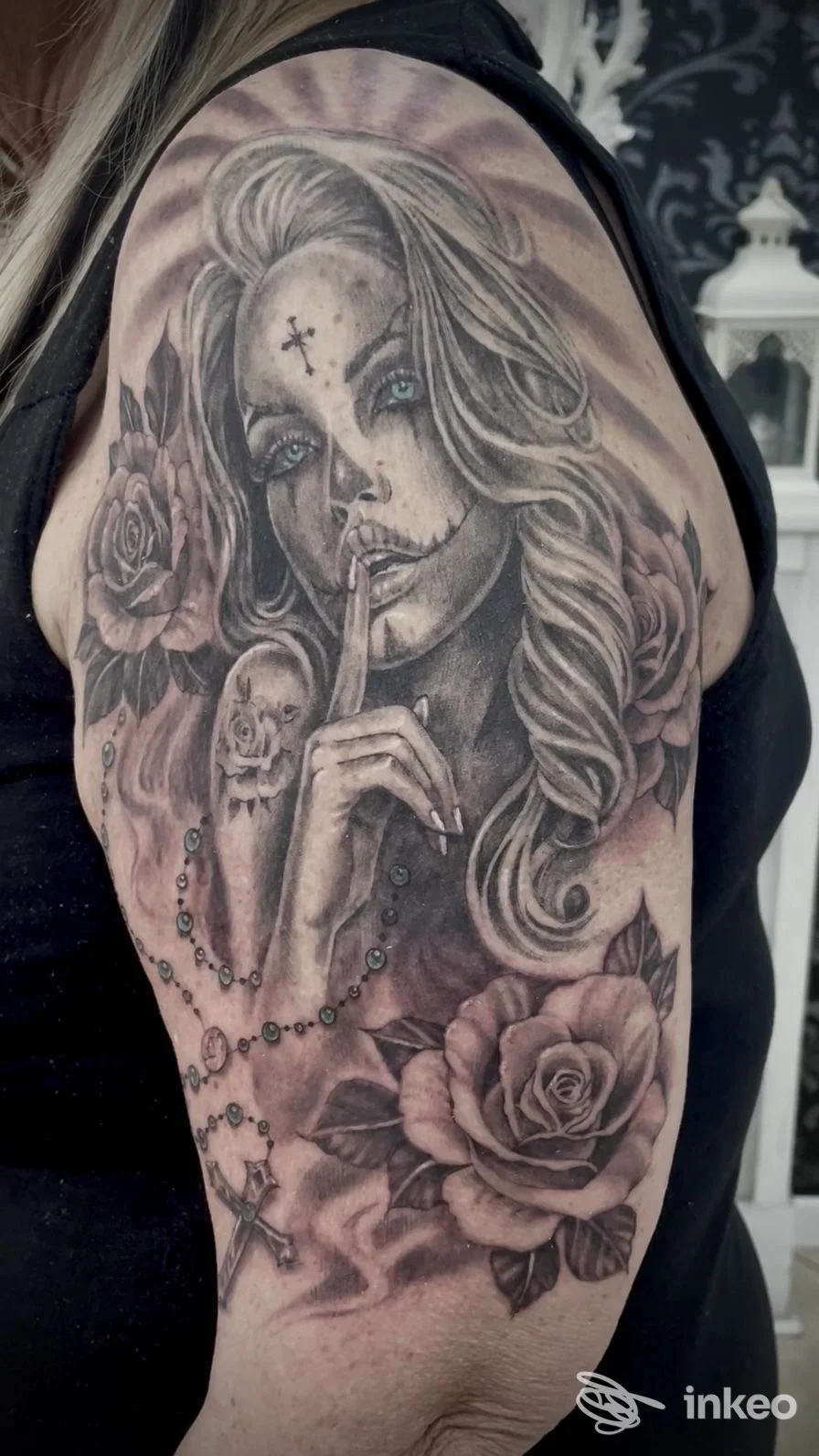 Grande tatuaggio realistico in bianco e nero su braccio superiore, ritratto femminile con rose e rosario - Dora Ink Art & Tattoo, Saonara.
