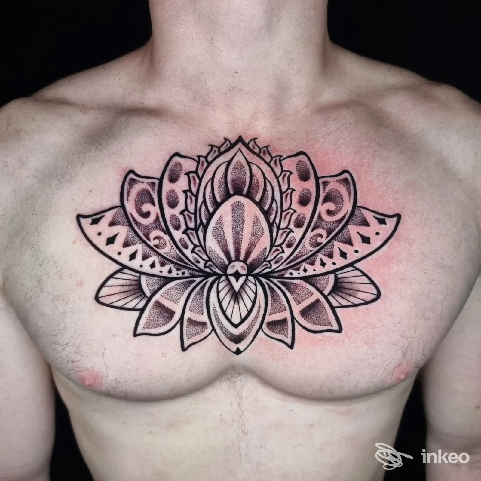 Tatuaggio ornamentale in bianco e nero a forma di fiore/mandala sul petto, scatto studio di Iguana Tattoo a Noale.