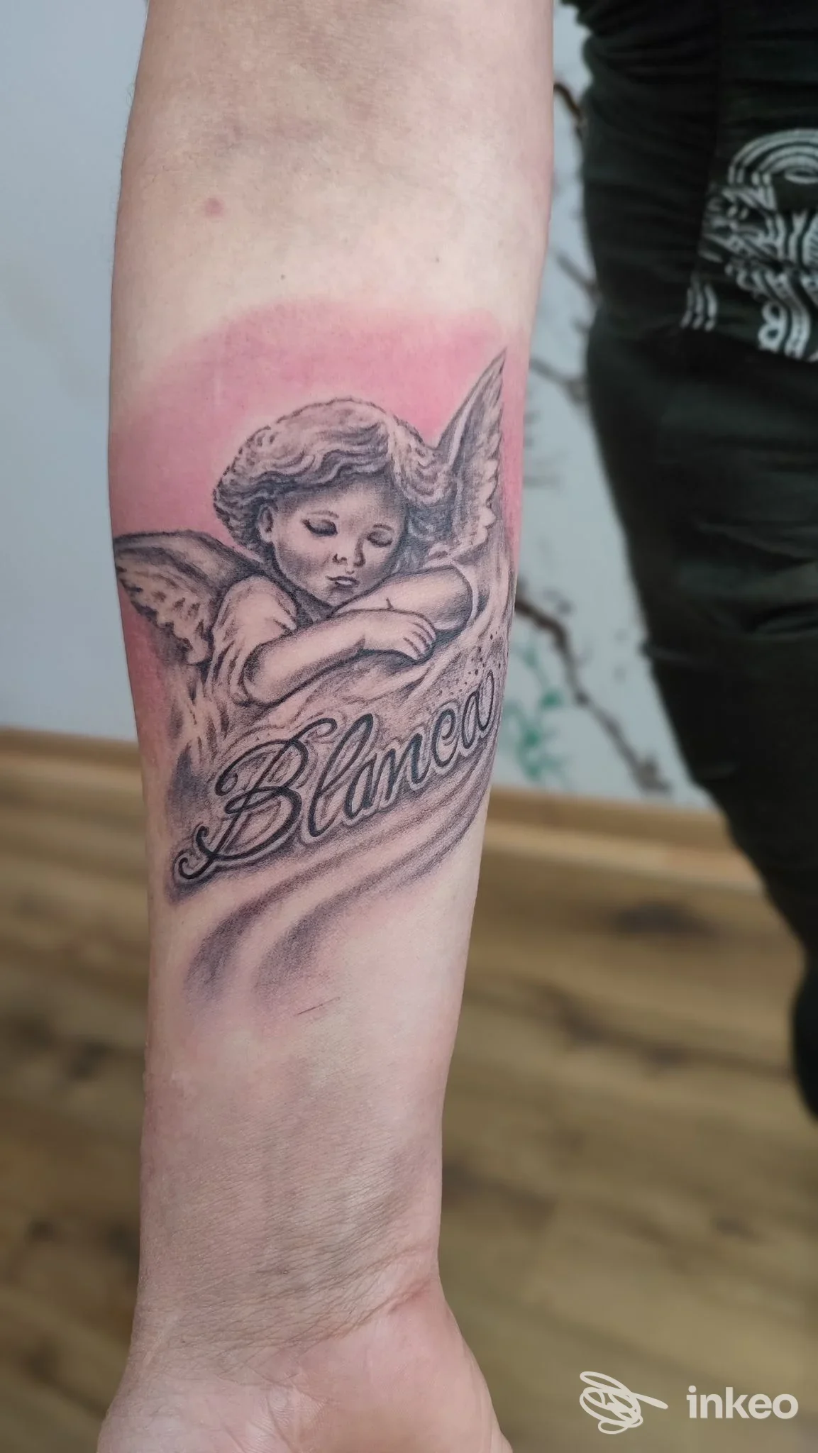 Tatuaggio su avambraccio con cherubino in bianco e nero e scritta "Blanca" – PERFECT CRIME TATTOO, San Stino di Livenza.