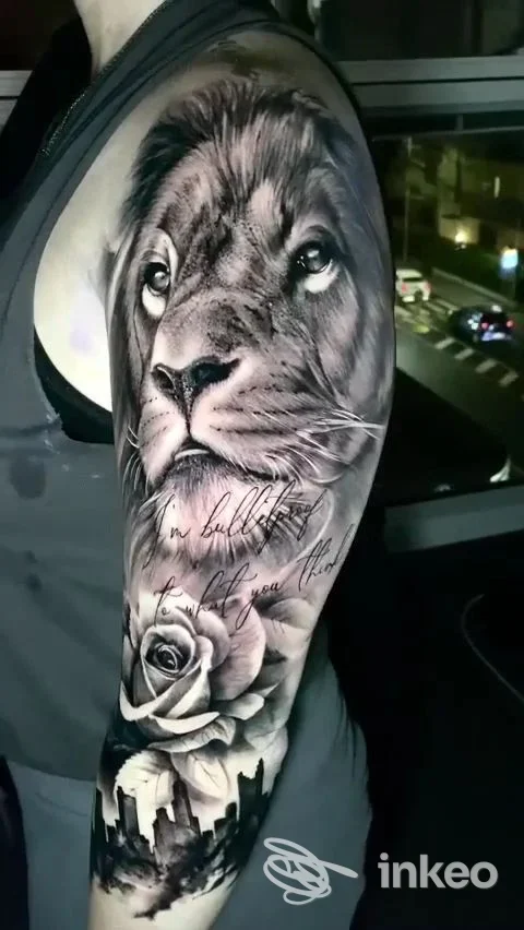 Grande tatuaggio realistico in bianco e nero di un leone, rosa e skyline sul braccio superiore. Trap Tattoo, Piove di Sacco.