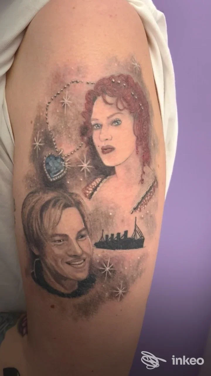 Tatuaggio sull'alto braccio con due ritratti, una collana a cuore e la sagoma di una nave. Speno TATTOO Lab, San Vito di Leguzzano.