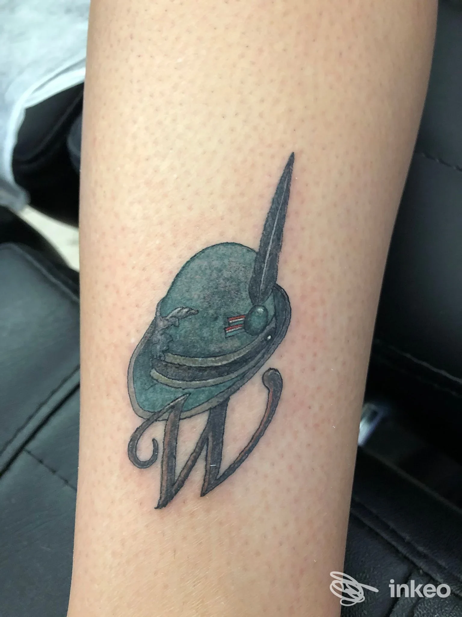 Tatuaggio su avambraccio interno: elmo verde scuro con dettagli neri e lettera 'W'. Speno TATTOO Lab, San Vito di Leguzzano.
