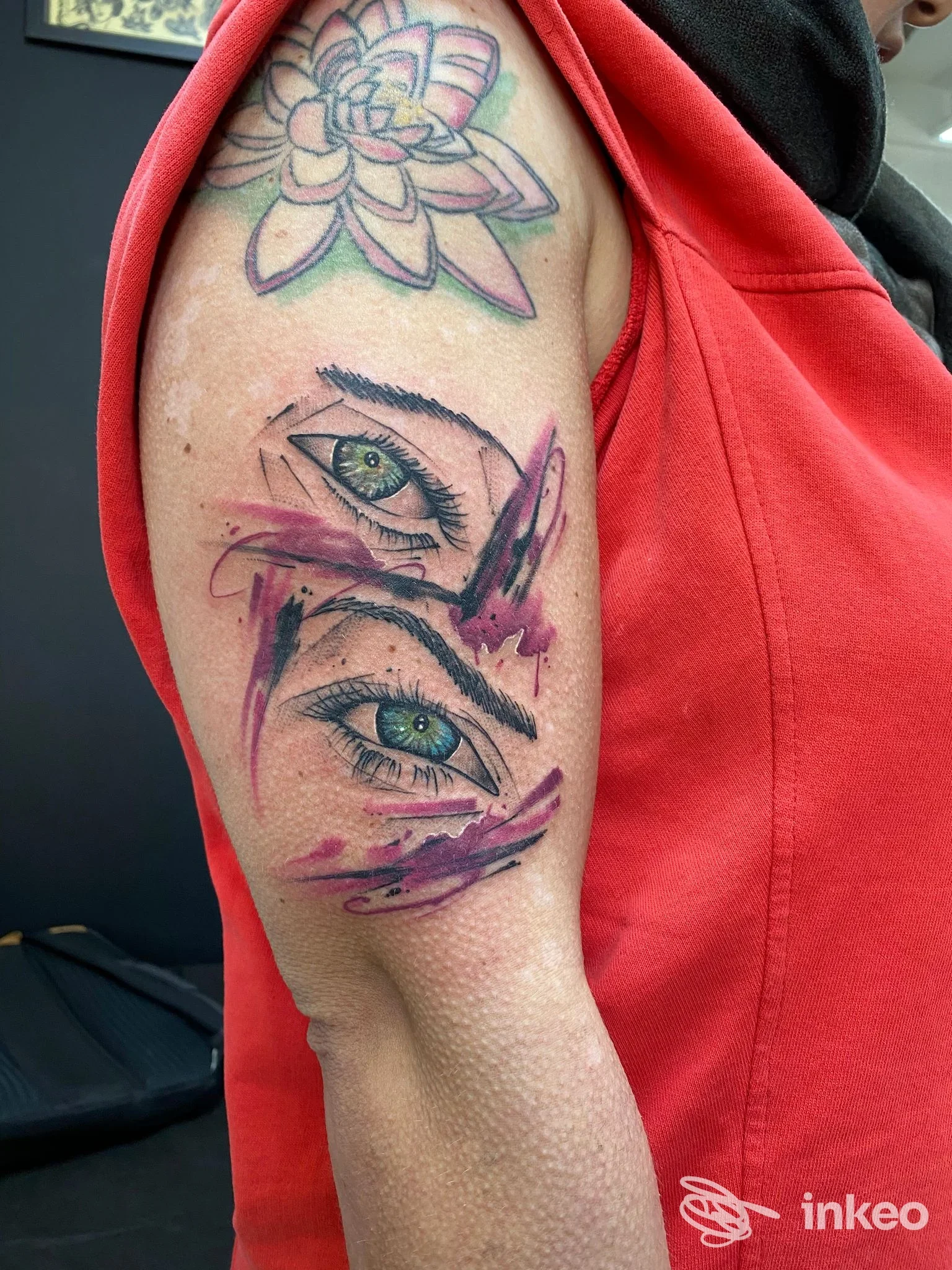 Tatuaggio su braccio superiore con due occhi realistici e sfumature rosa; immagine fornita da Alchemy Tattoo Studio, Porto Recanati.