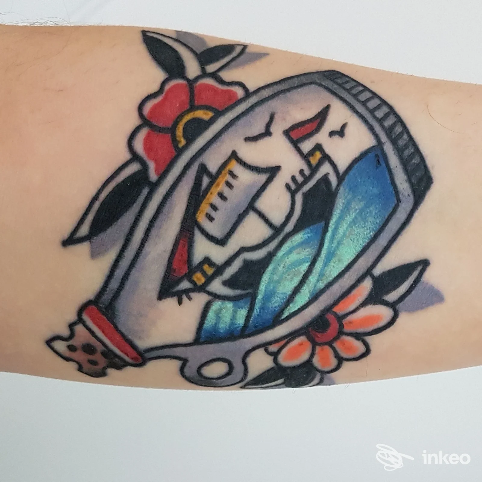 Tatuaggio stile tradizionale di una barca in bottiglia con fiori, eseguito da BarbieSlayer Tattoo a Macerata, su avambraccio.