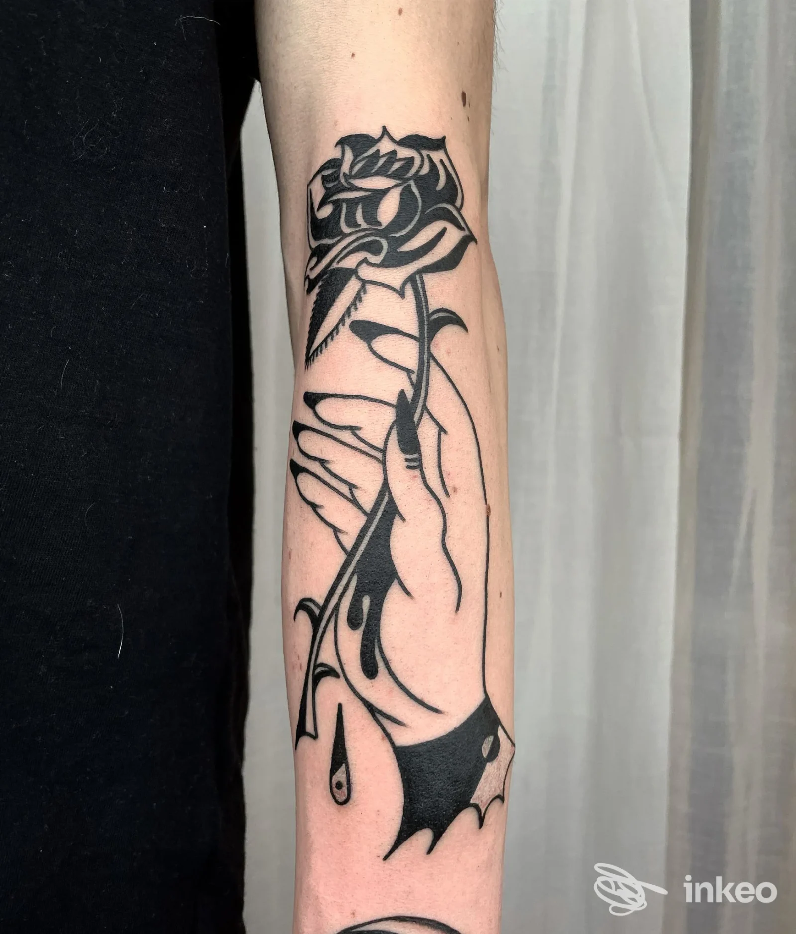 Tatuaggio blackwork di una mano che tiene una rosa sull'avambraccio, eseguito da Black Crow Tattoo a Pesaro.