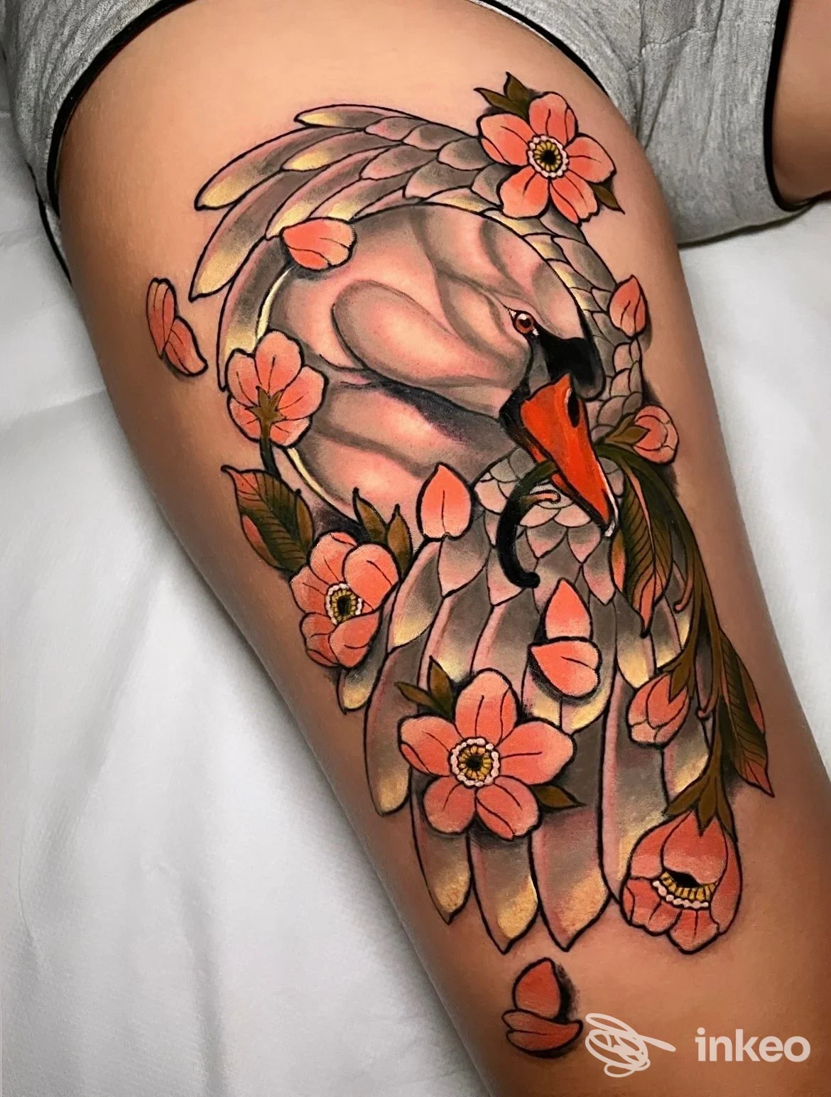 Tatuaggio colorato di cigno avvolto da fiori sul lato superiore della coscia, lavoro fotografato da Bloom tattoo studio a Porto Sant'Elpidio, dettaglio nitido.