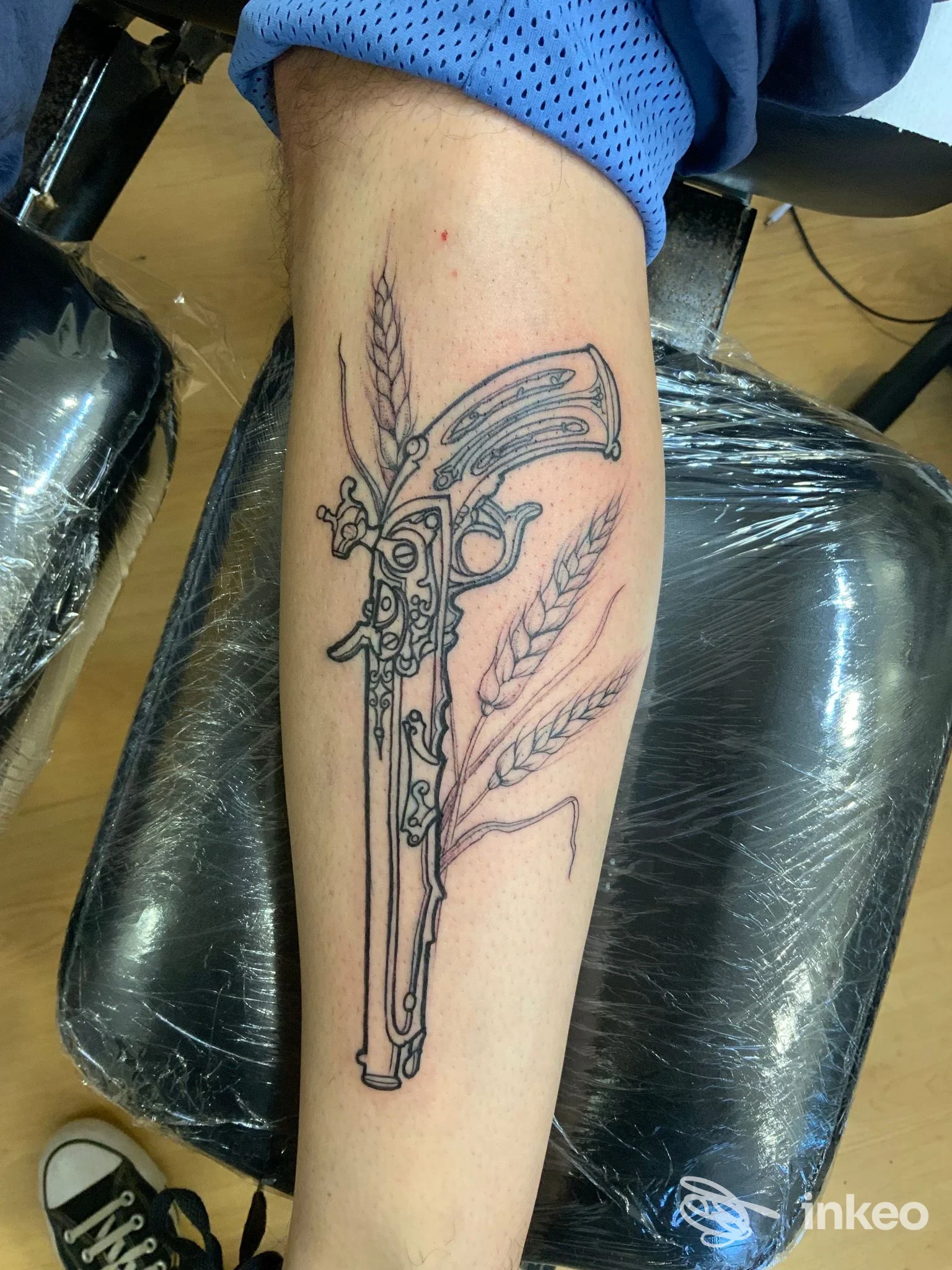 Tatuaggio linework su avambraccio con pistola antica e spighe, foto fornita da Crazy Horse Tattoo Studio a Falconara Marittima.