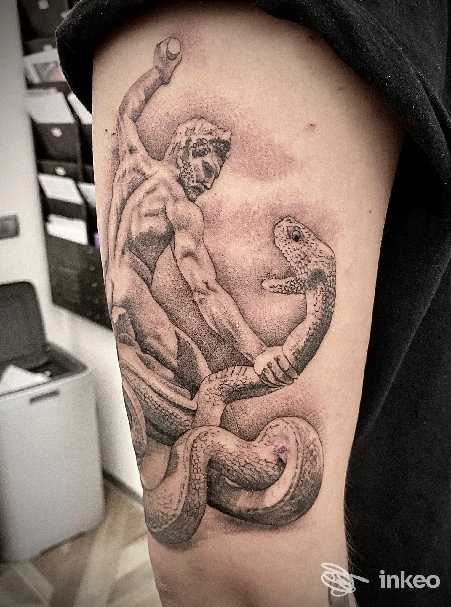 Tatuaggio realistico in bianco e nero sul braccio superiore: figura statuaria che afferra un serpente. DanyArt Tattoo di Danilo Todini, Esanatoglia.