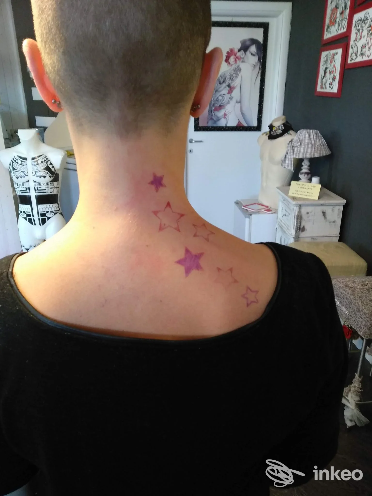 Collo e parte superiore della schiena con stelle tatuate rosa-viola; foto scattata nello studio Dayaks Tattoo a Pesaro.