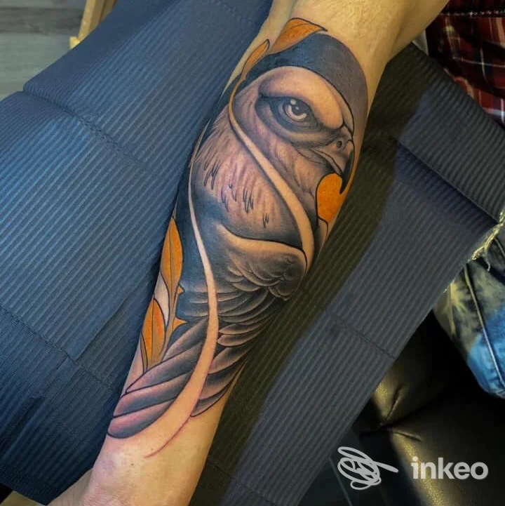 Tattoo a colori di un pesce lungo l’avambraccio sinistro, con sfumature blu, viola e arancione, su sfondo neutro.