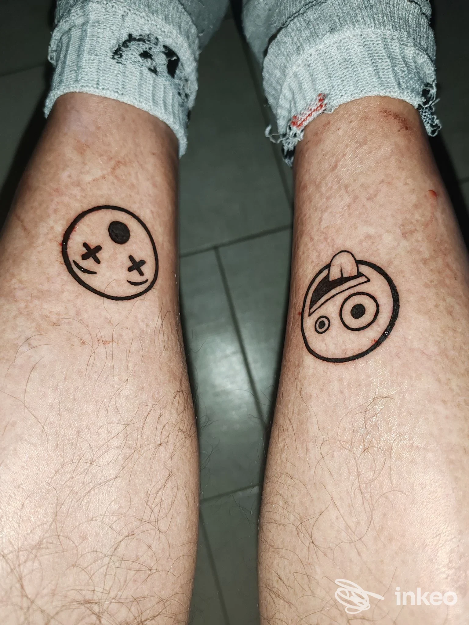 Due piccoli tatuaggi minimal in nero sui polpacci in primo piano, fotografia dello studio Diletta Tattoo Vision a Tolentino.