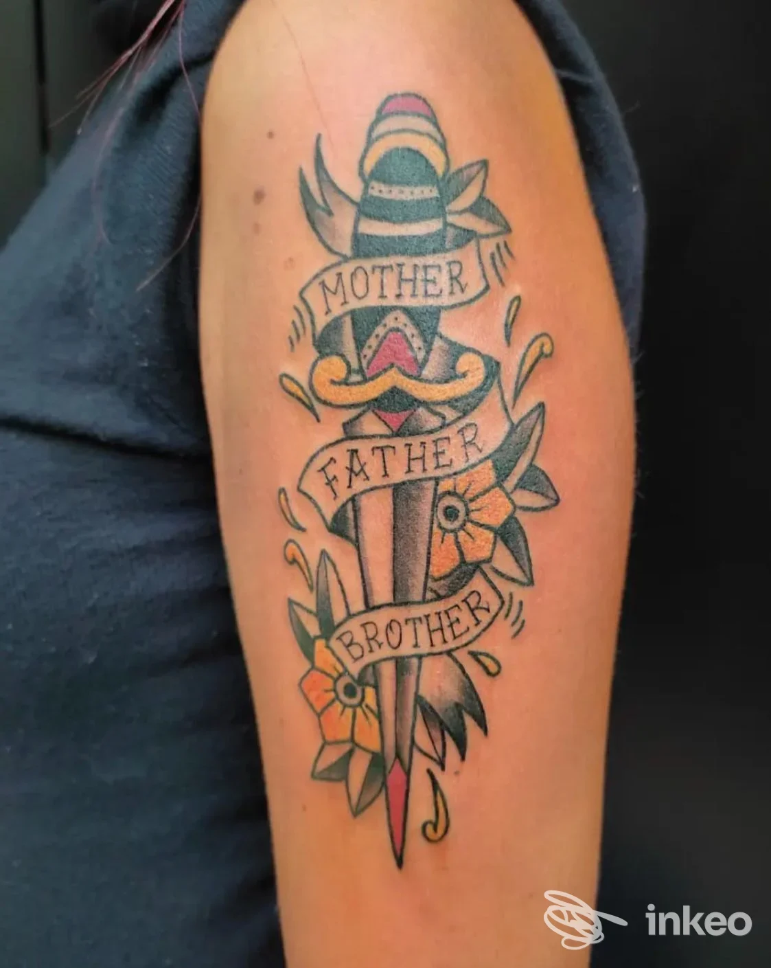 Tatuaggio tradizionale a pugnale con fiori e nastri 'Mother Father Brother' sul braccio, Fun House Tattoo Shop, Macerata.